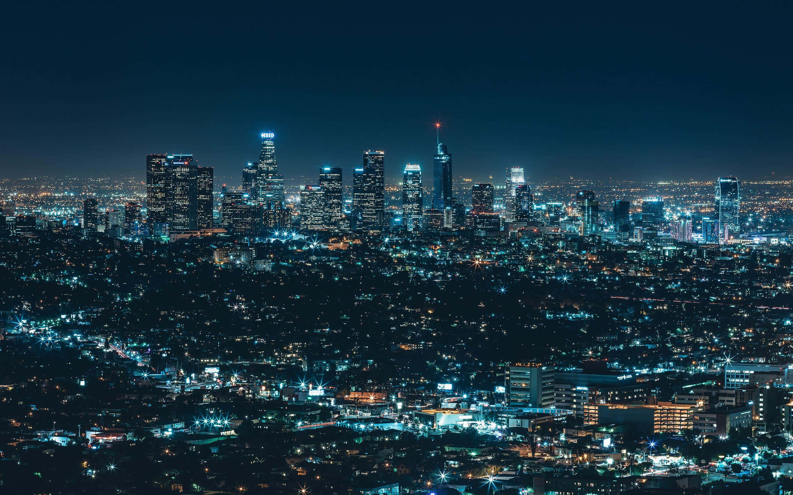 洛杉磯城市夜景 壁紙 — 廣闊的城市夜景，高聳的摩天大樓和發光的街道在黑暗的天空下。