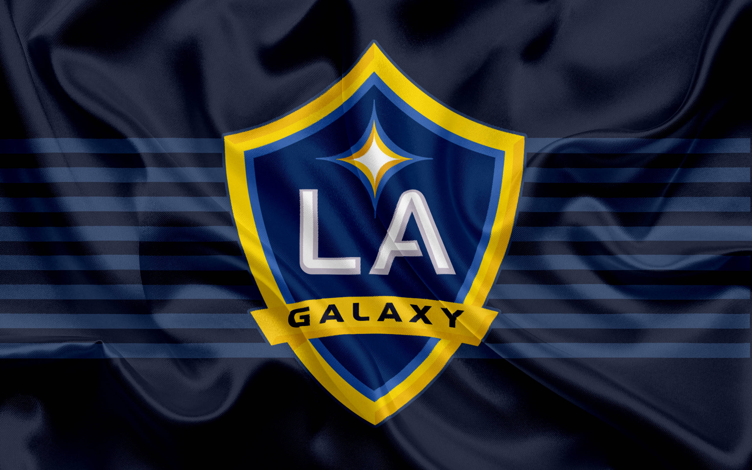 洛杉磯銀河在行動——足球 Mastery 的動態展現 壁紙 — LA Galaxy 足球隊標誌居中於深藍色緞面旗幟上，帶有水平條紋和星爆徽章。