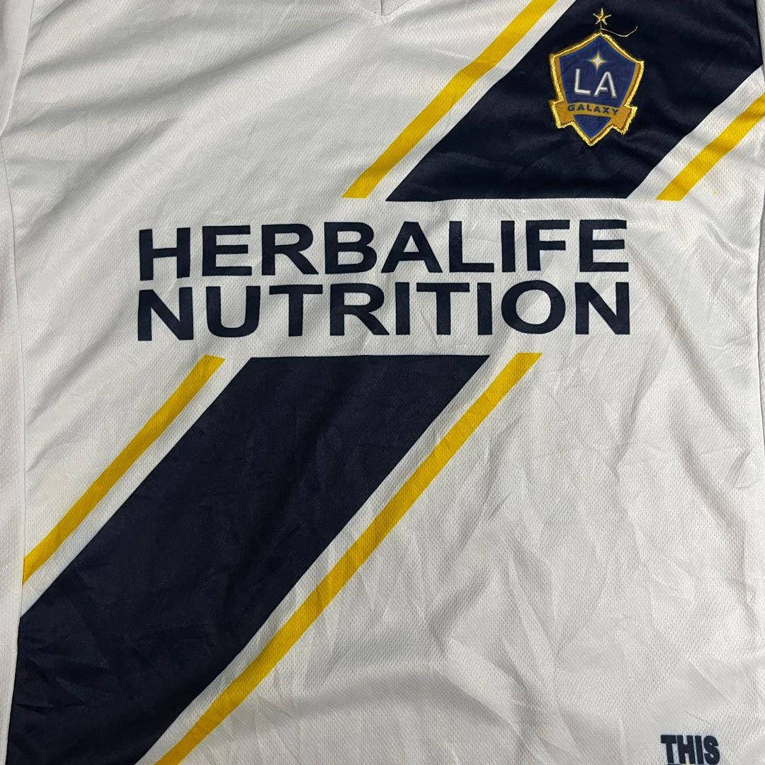 洛杉磯銀河與Herbalife Nutrition贊助協議 壁紙 — 白色洛杉磯銀河足球球衣近照，帶有Herbalife Nutrition贊助及海軍藍黃色斜紋。