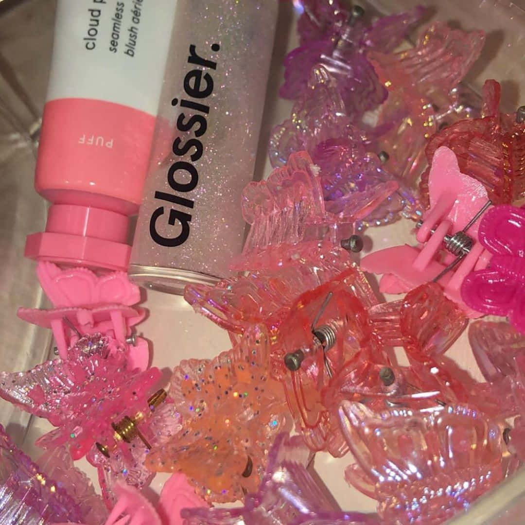 粉紅色閃亮蝴蝶髮夾和Glossier化妝品在容器中。
