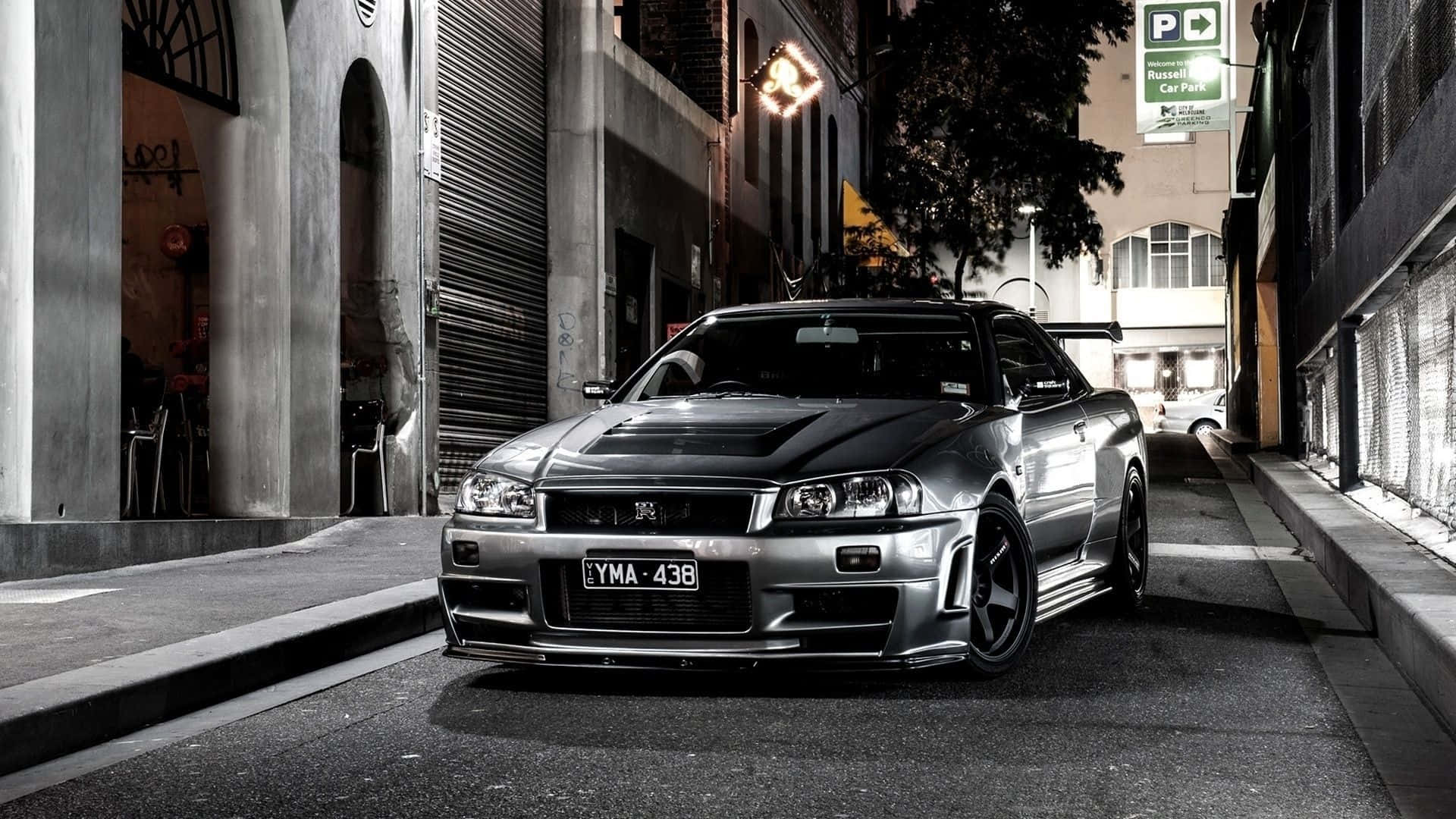 銀色日產Skyline R34在夜間停放在狹窄的城市小巷中。