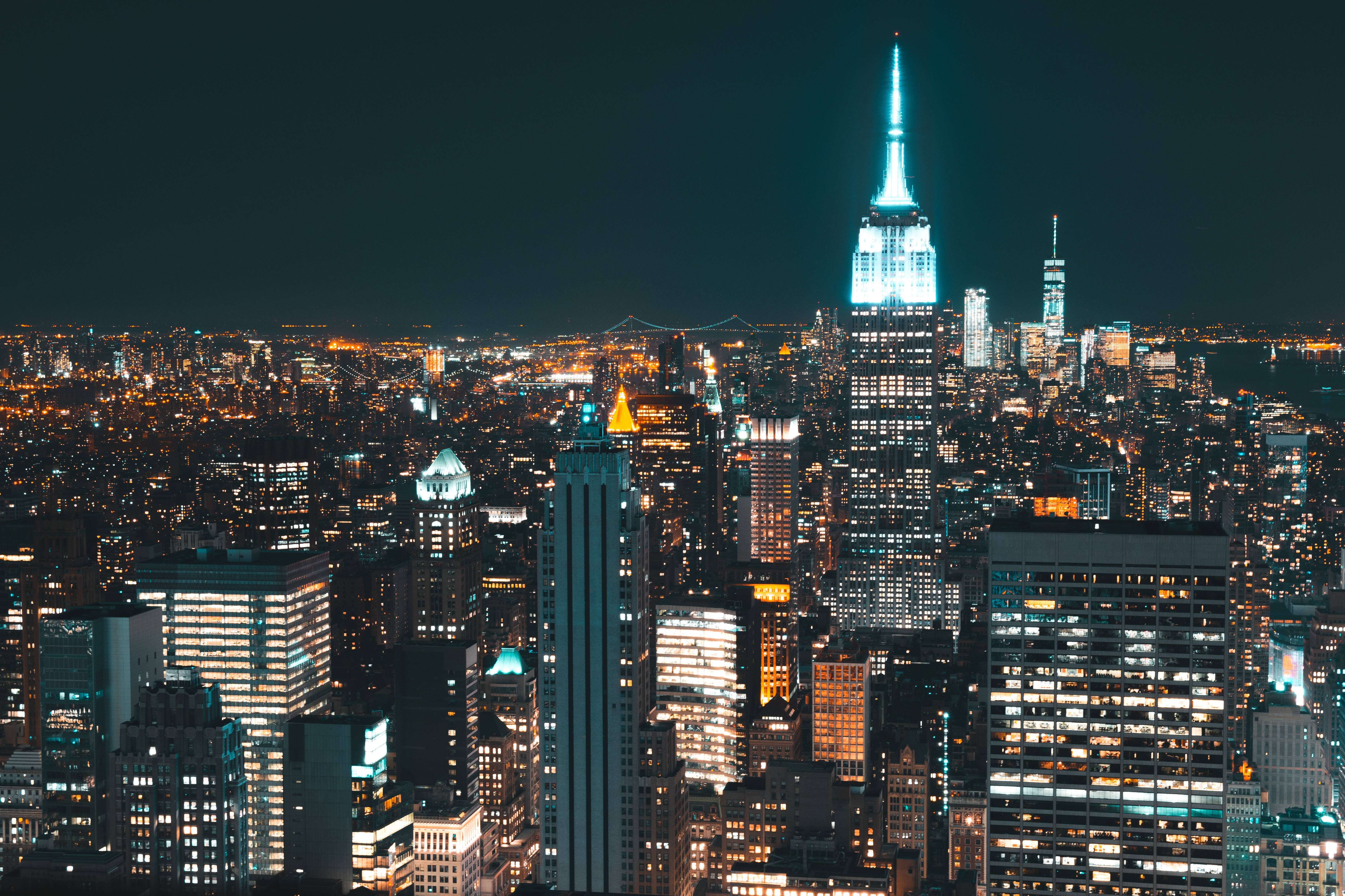 活力四射的4K紐約市 壁紙 — 紐約令人驚嘆的夜景，帝國大廈發出藍色光芒，周圍的摩天大樓則以溫暖的琥珀色照亮。