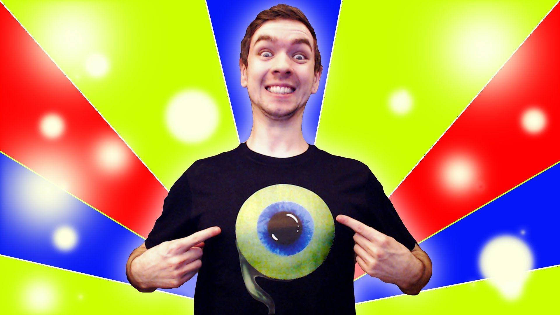 活力四射的Jacksepticeye 壁紙 — 一名身穿黑色T恤、上面有巨大眼睛圖案的男人，在充滿活力的紅、藍、綠放射狀背景和發光球體前指著它。