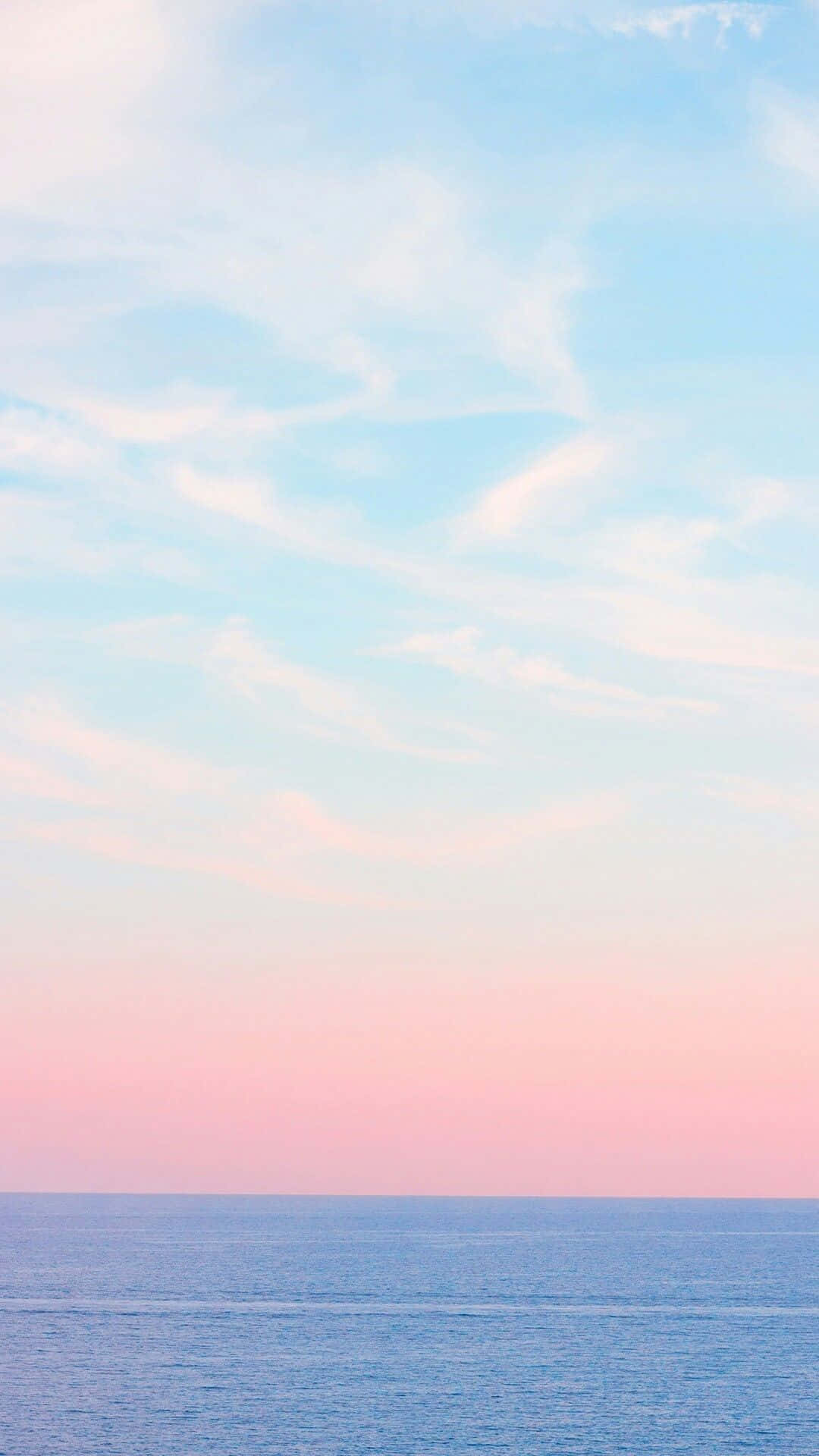 平靜海洋上空的黎明粉彩粉紅與藍色天空