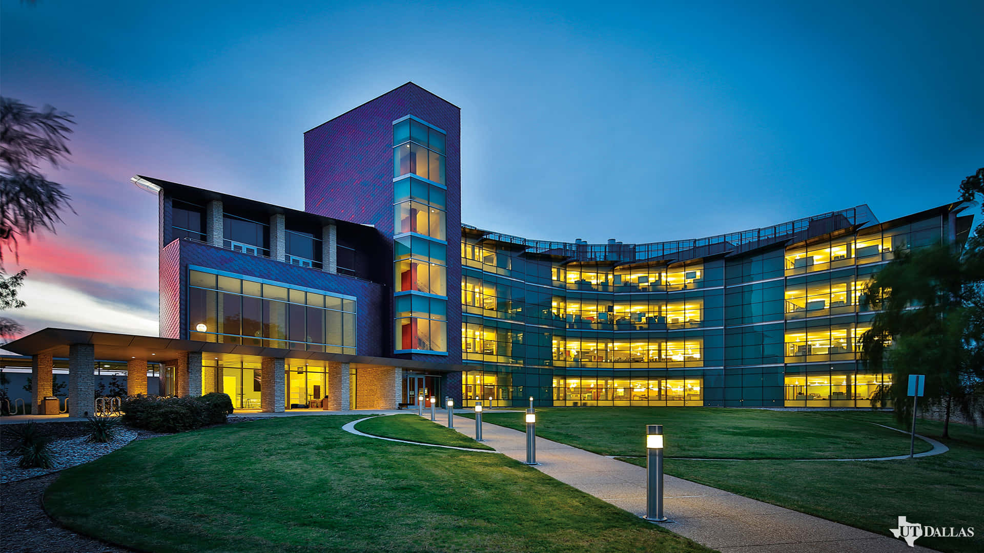 現代大學建築在黃昏時亮起發光的窗戶和景觀化的場地。