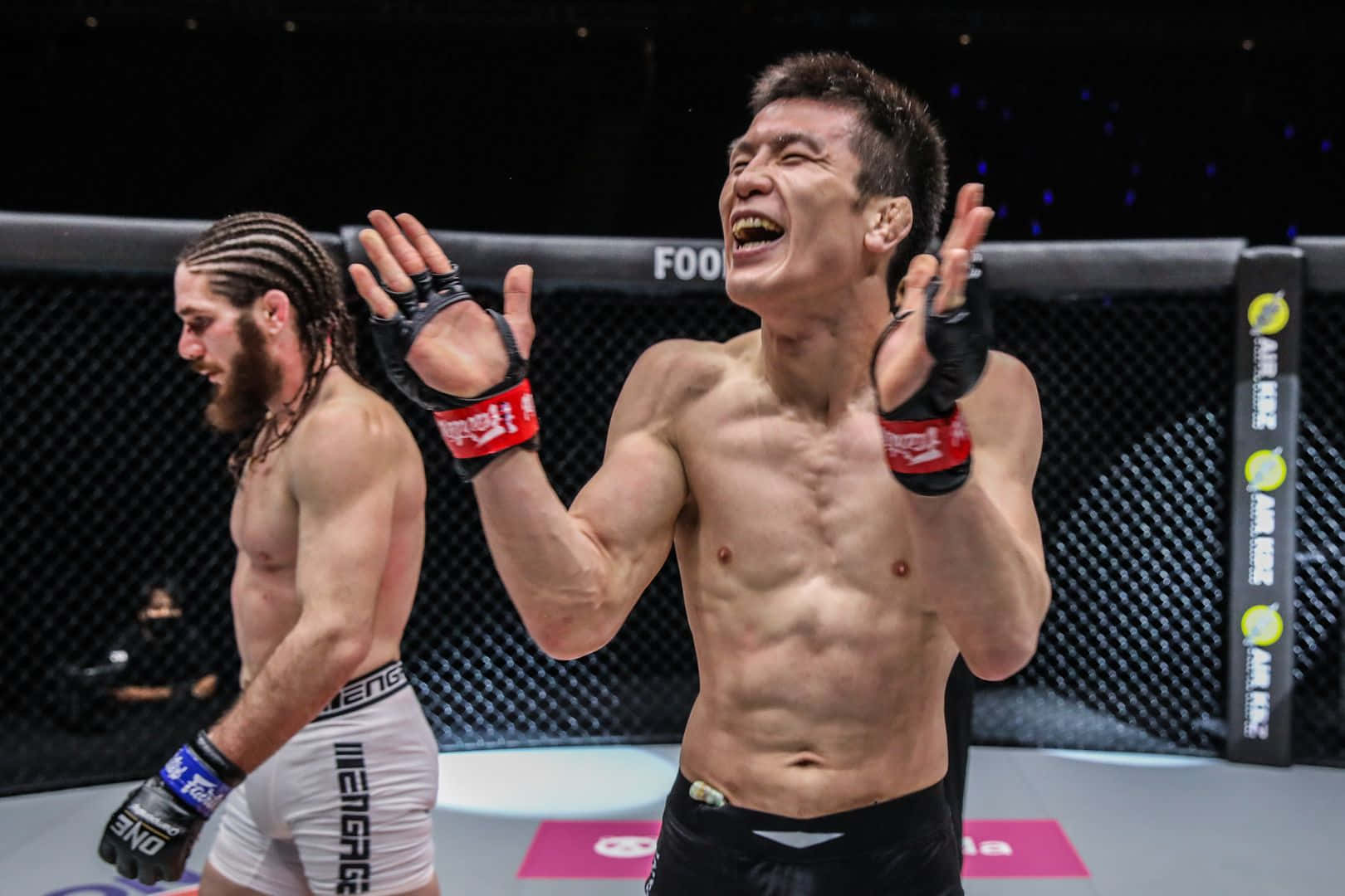 活力四射的青木真也擊掌慶祝 壁紙 — 一位勝利的MMA拳手在八角籠中狂野慶祝，而他的對手則敗走離場。