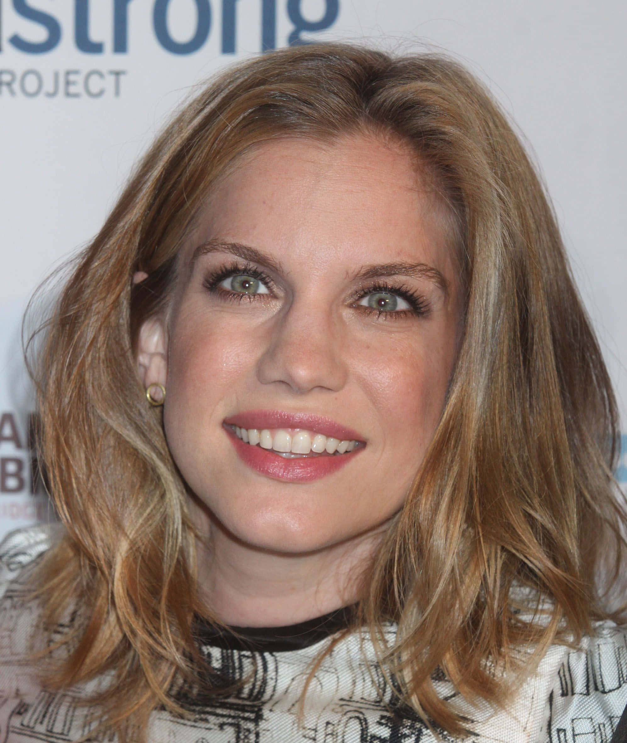 anna chlumsky 桌布 壁紙 — 活動中一位微笑女性嘅特寫肖像，佢有波浪形金髮同綠色眼睛。