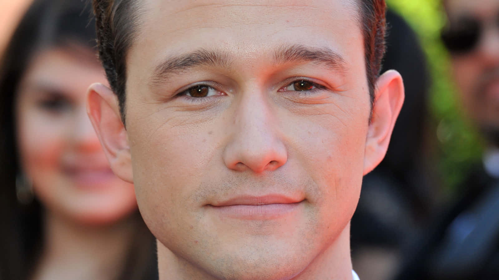 joseph gordon-levitt 桌布 壁紙 — 活動中一名男子的特寫肖像，帶有溫暖燈光和模糊的背景人物。