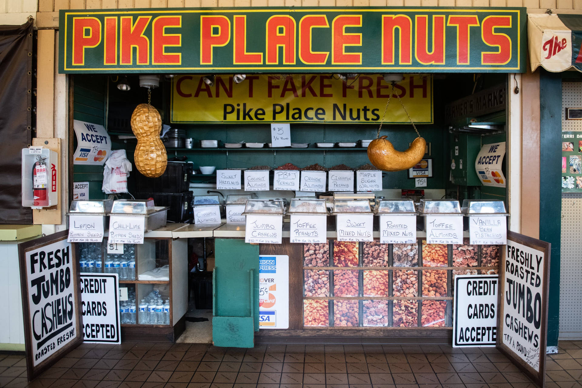 Pike Place堅果市場攤位，玻璃容器裝著烤堅果和懸掛的花生。