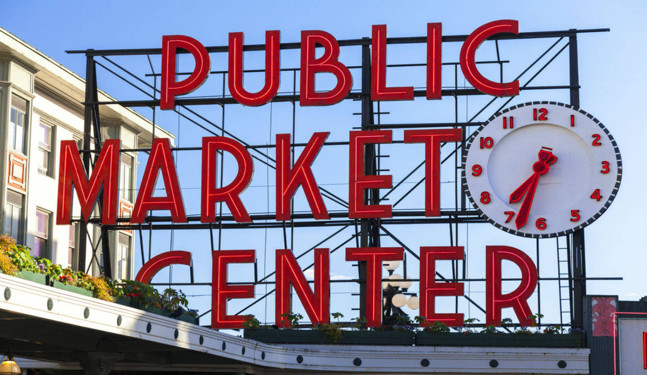 Public Market Center 的紅色標誌，帶有一個大時鐘，在藍天下顯示 7:35。