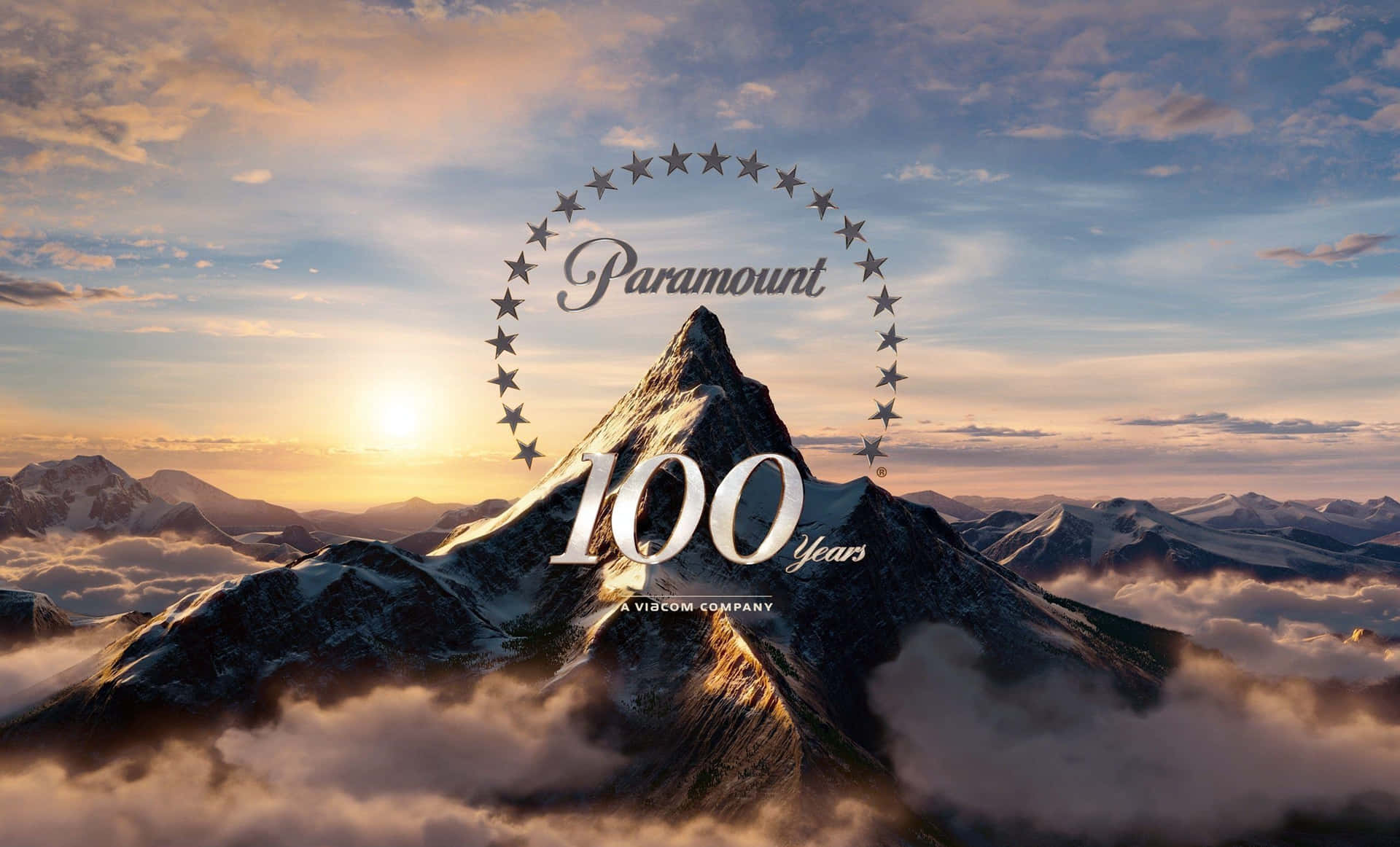 日出時雪山上的派拉蒙100 Years標誌。