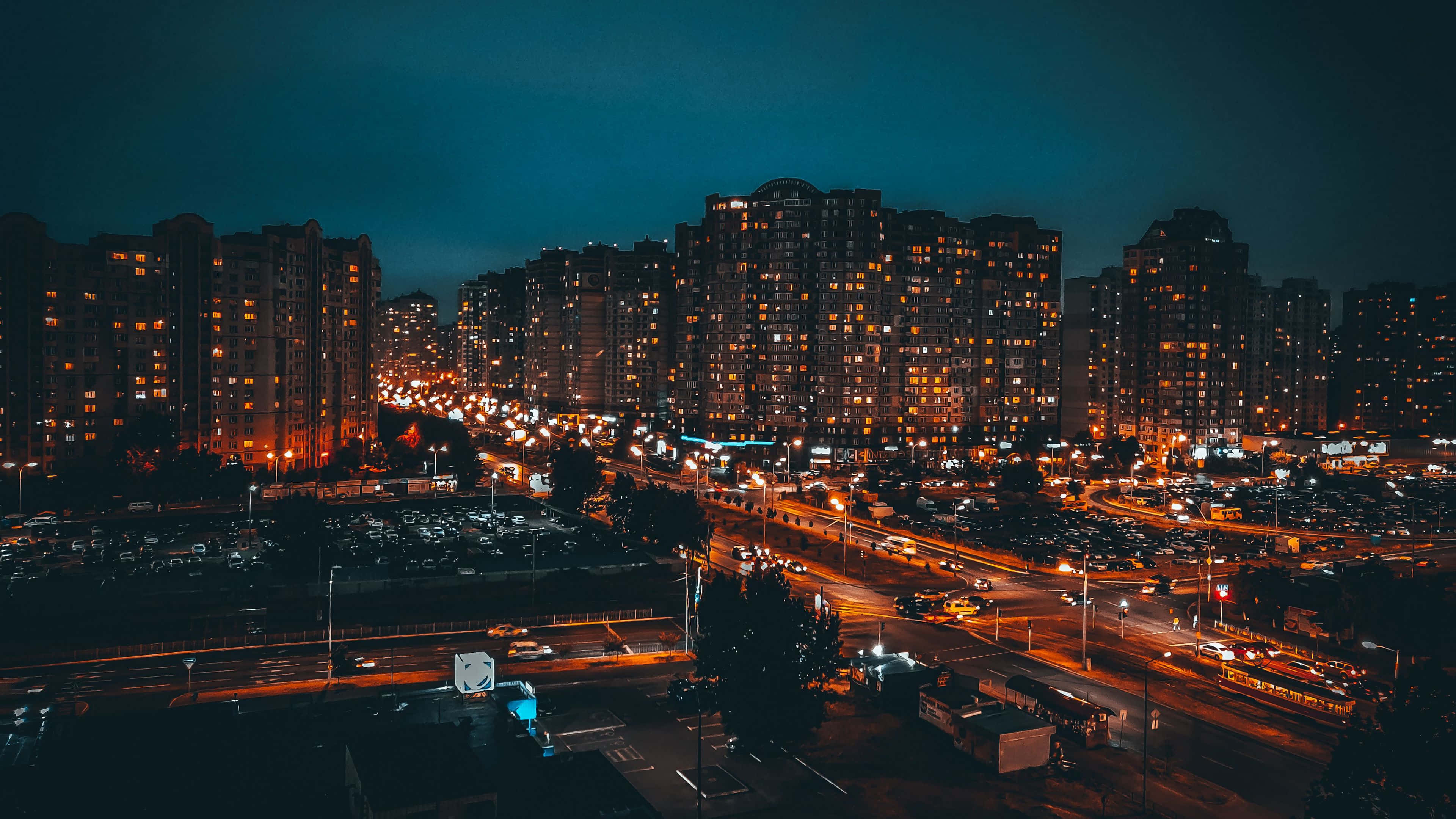 流光溢彩夜景城市 壁紙 — 廣闊的城市夜景，高樓大廈的窗戶閃爍著光芒，繁忙道路上汽車燈光劃出線條。