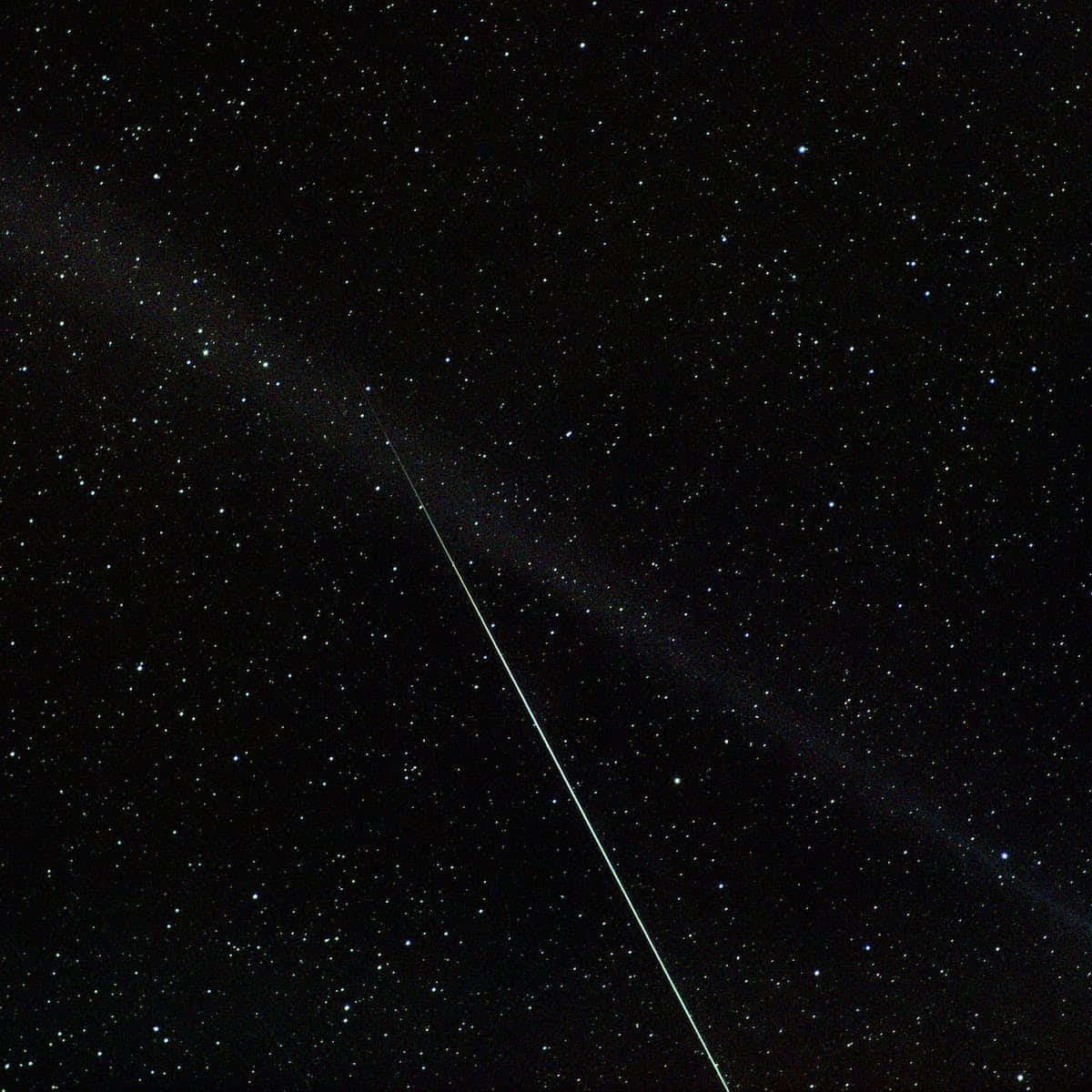流星劃過夜空，閃耀藍綠光芒 壁紙 — 一顆明亮的流星斜斜劃過滿天星斗的夜空，背景中隱約有星雲發光。