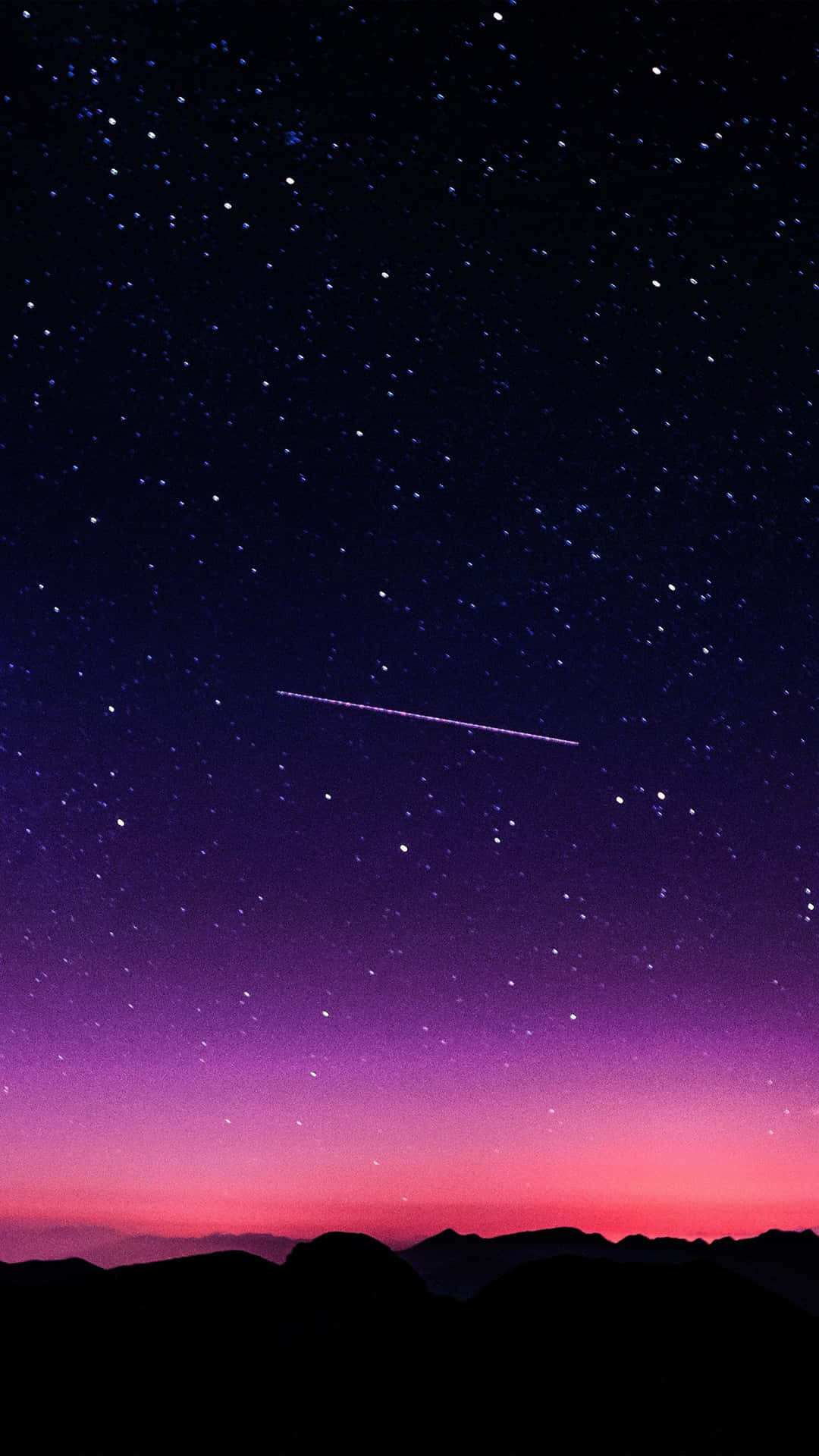 一顆流星劃過黑暗山脈輪廓上方的星空暮色天空。
