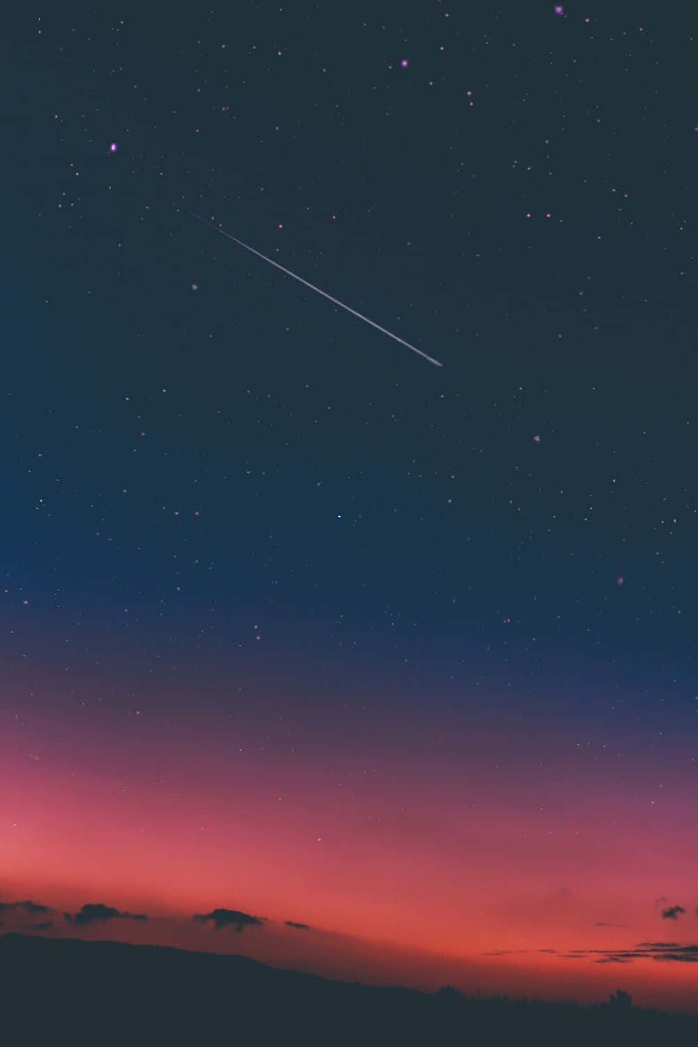一顆流星越過黑暗山丘上的暮色天空。