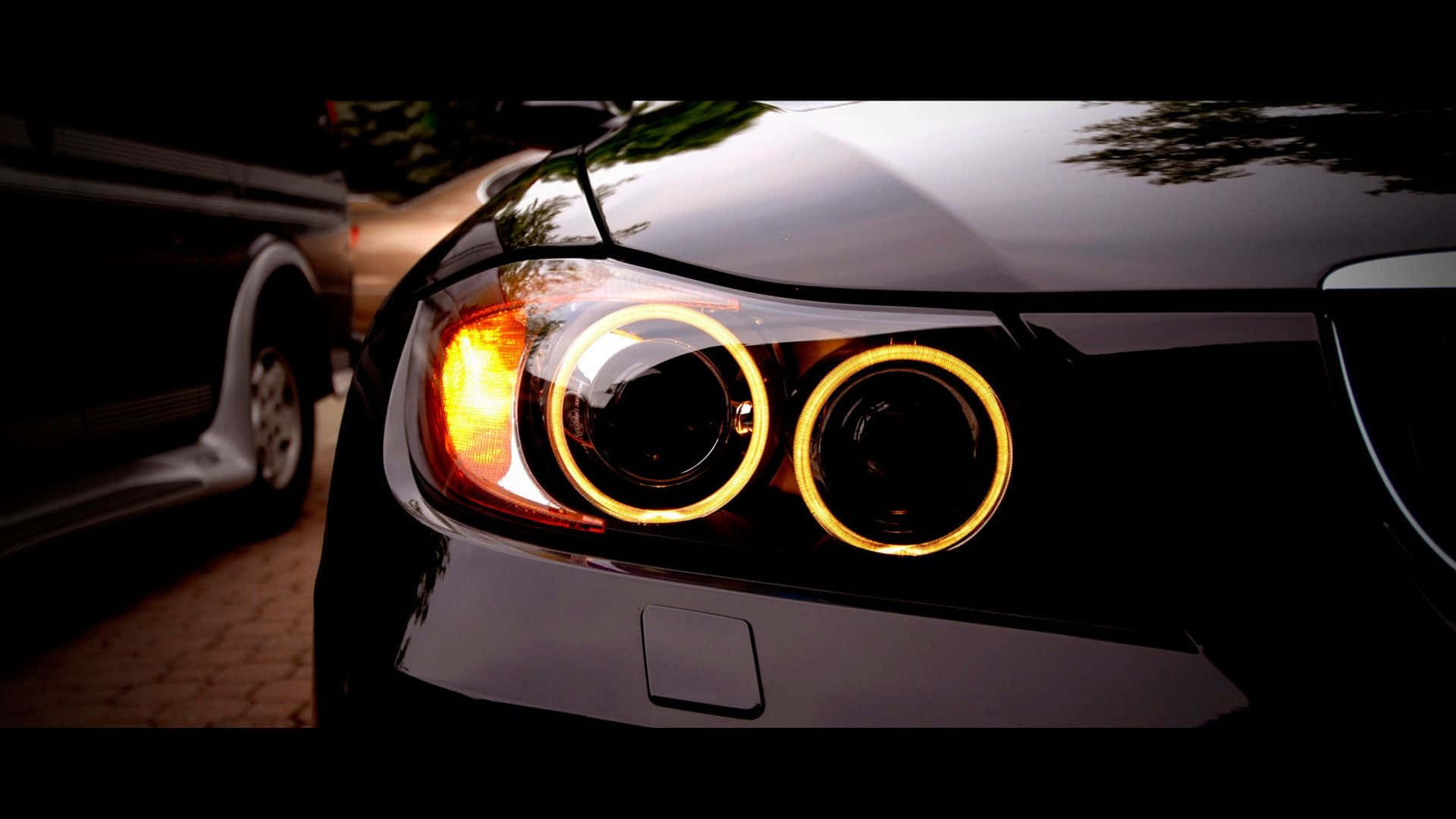 夜間黑色汽車發光光環頭燈的特寫。