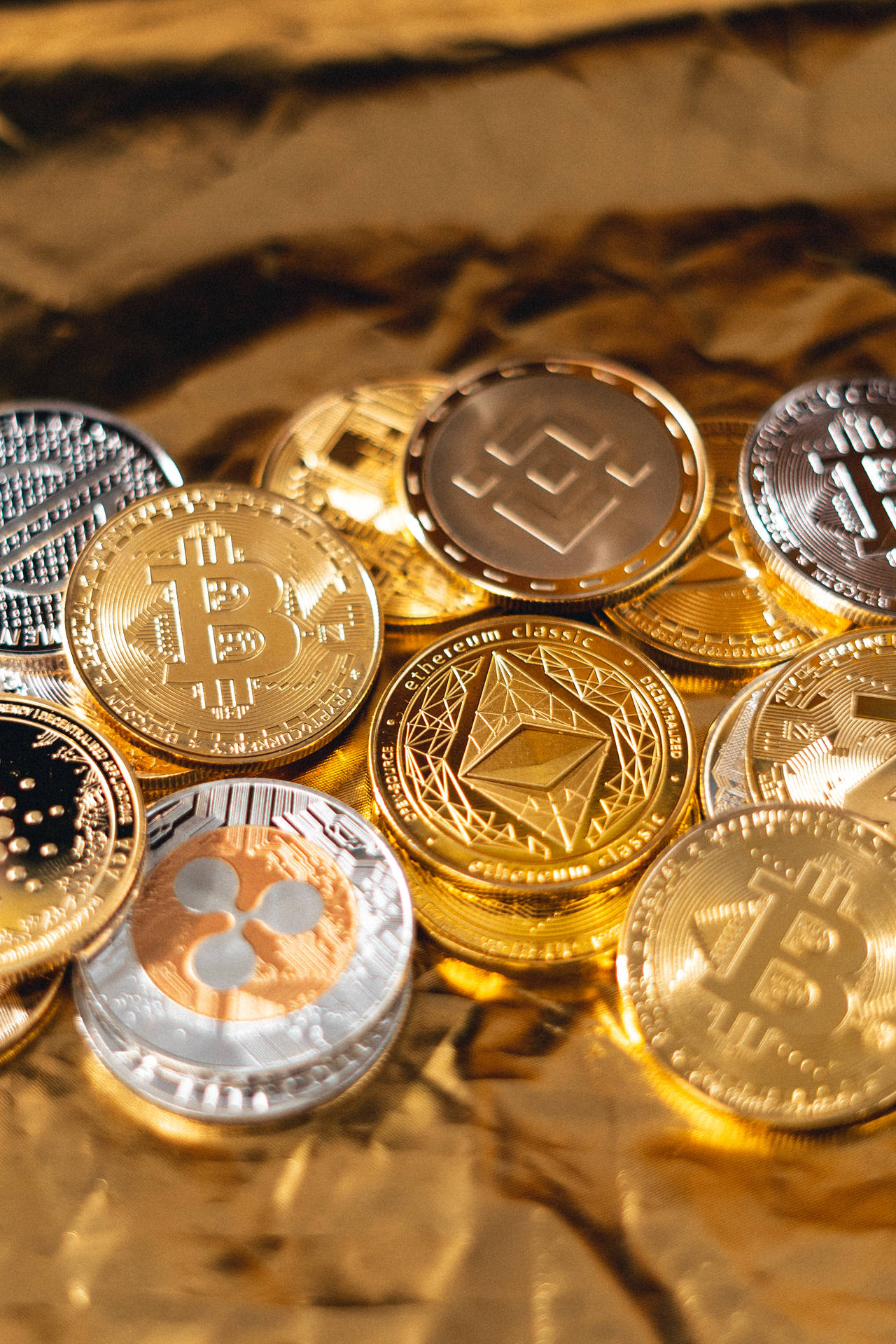 在溫暖的燈光下，堆疊的加密貨幣硬幣放在金箔上。