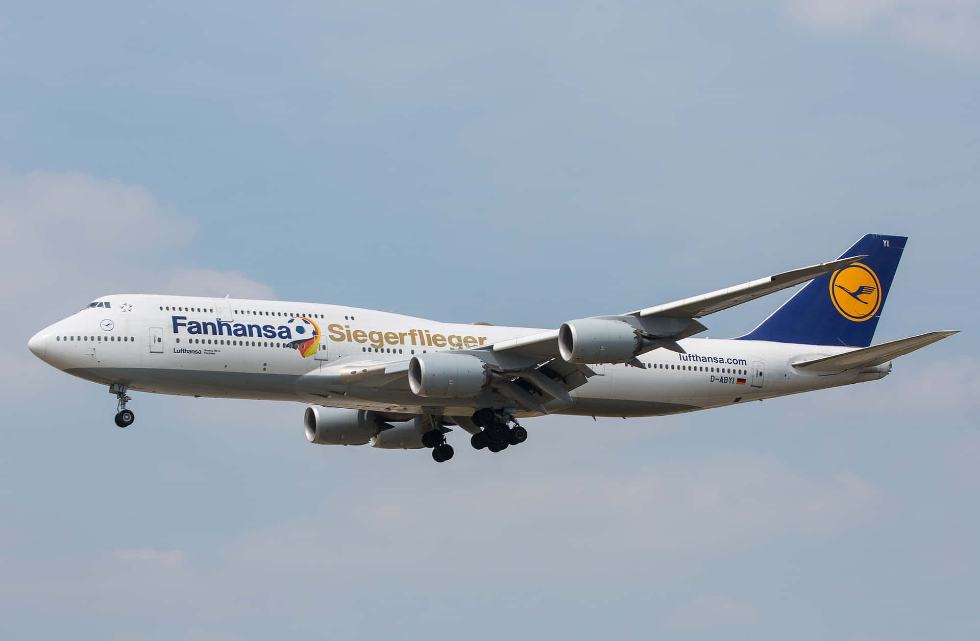 漢莎航空波音747飛機在飛行中，起落架放下，背景為多雲的天空。