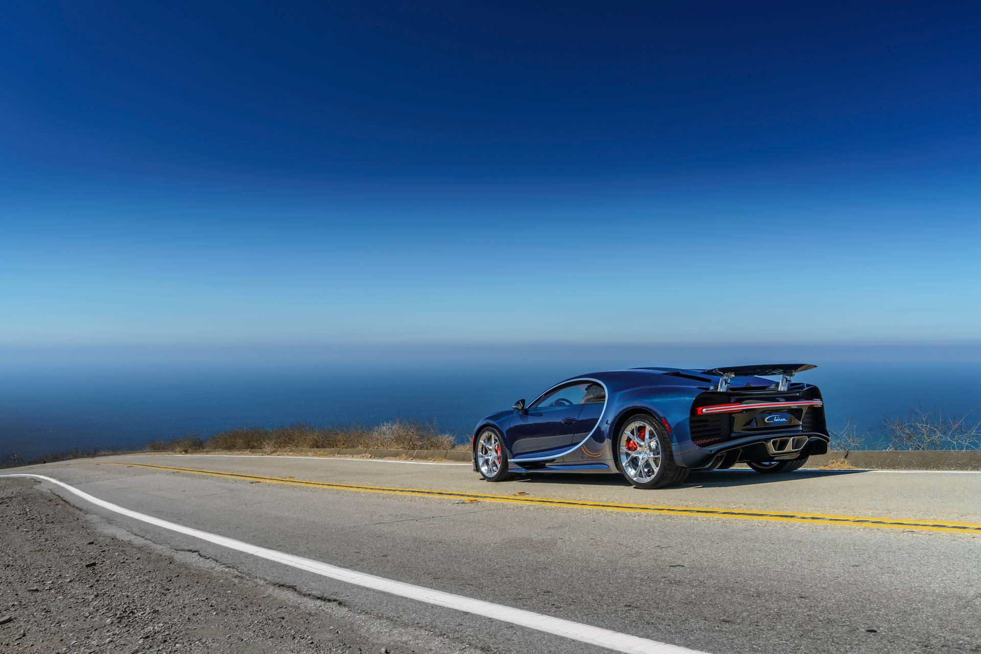 日落時分，藍色 Bugatti Chiron 在沿海公路上俯瞰海洋。