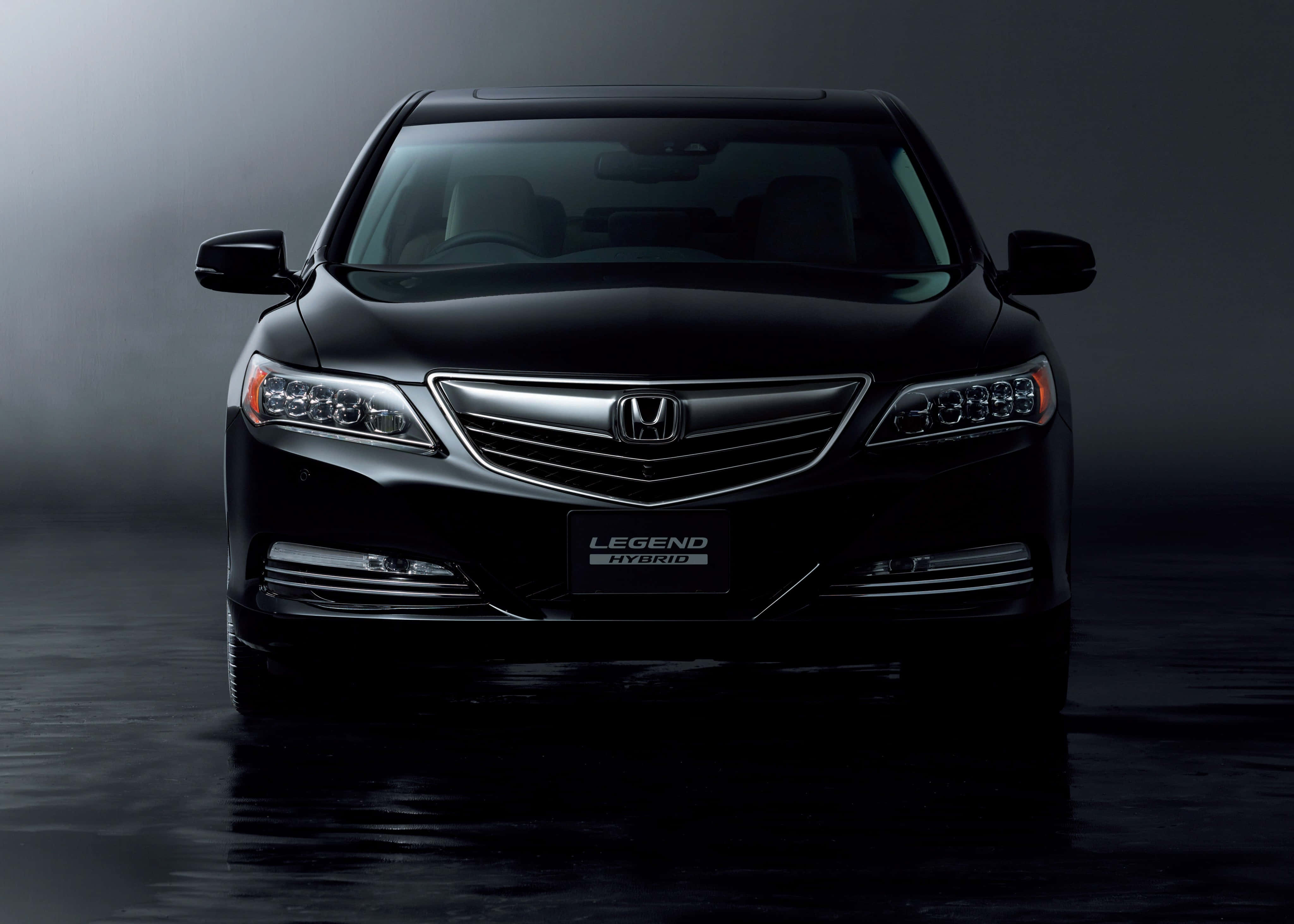 流線型時尚本田Legend行駛中 壁紙 — 一輛時尚的黑色本田 Legend Hybrid 轎車在戲劇性的攝影棚燈光下閃耀，下方是反射性的濕潤路面。