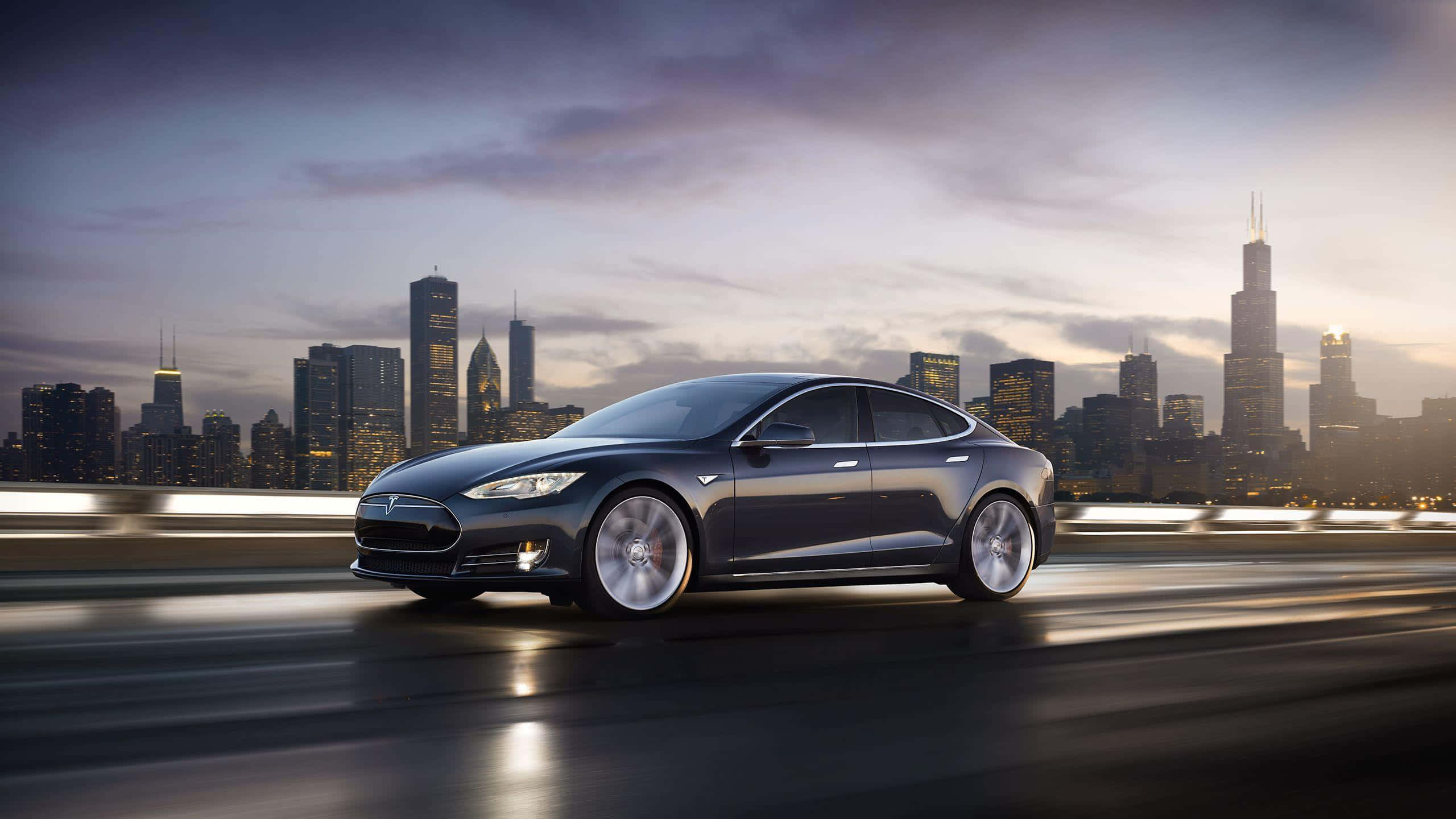 流線型特斯拉 Model 3 高端電動車 壁紙 — 一輛時尚的深灰色Tesla Model S在高速公路上飛馳，芝加哥璀璨的天際線在黃昏時分於其後閃耀。