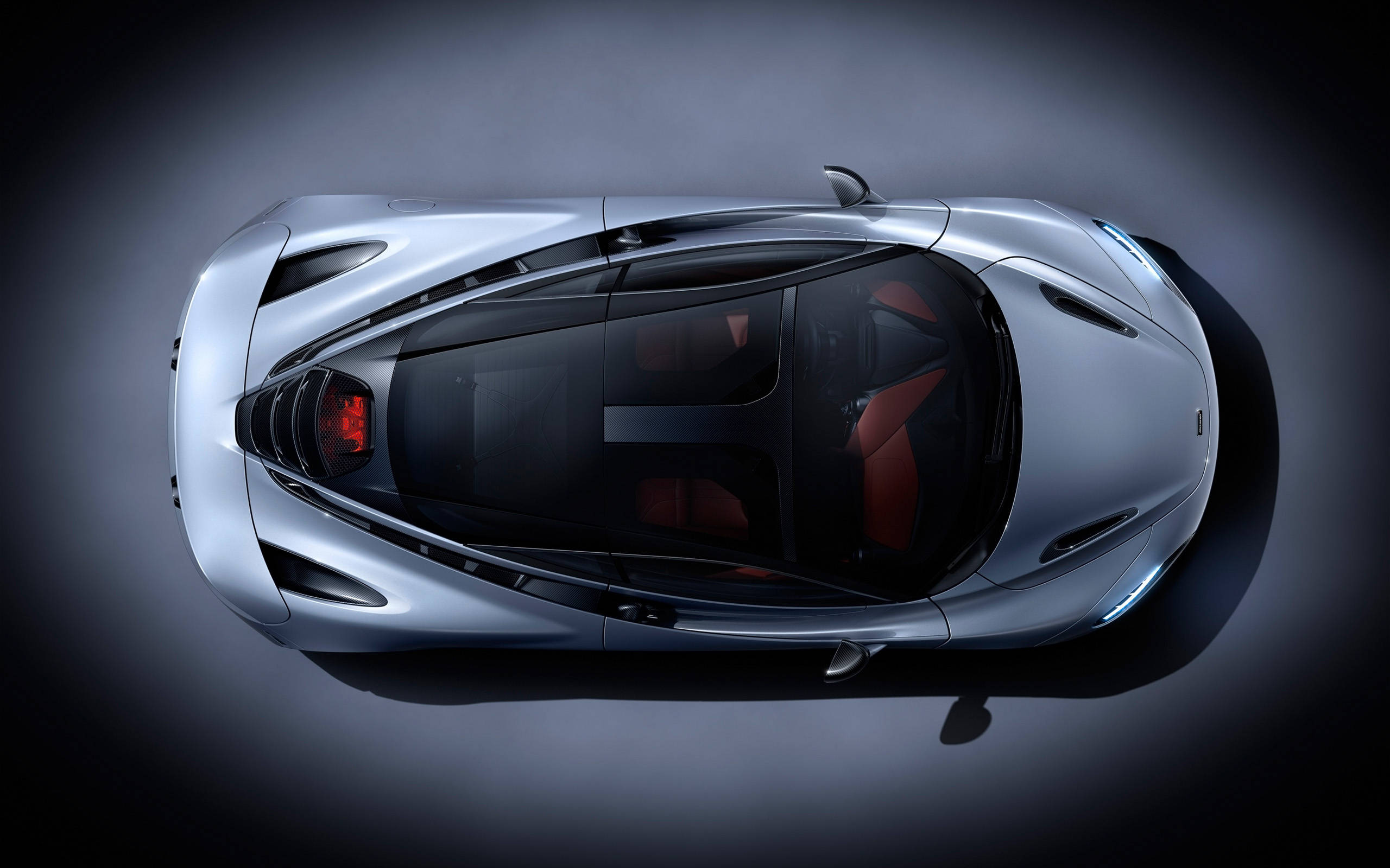 流線型麥拉倫720S 4K 壁紙 — 從上方俯瞰的時尚銀色跑車，配備紅色內飾座椅和發光尾燈，背景為深色工作室。