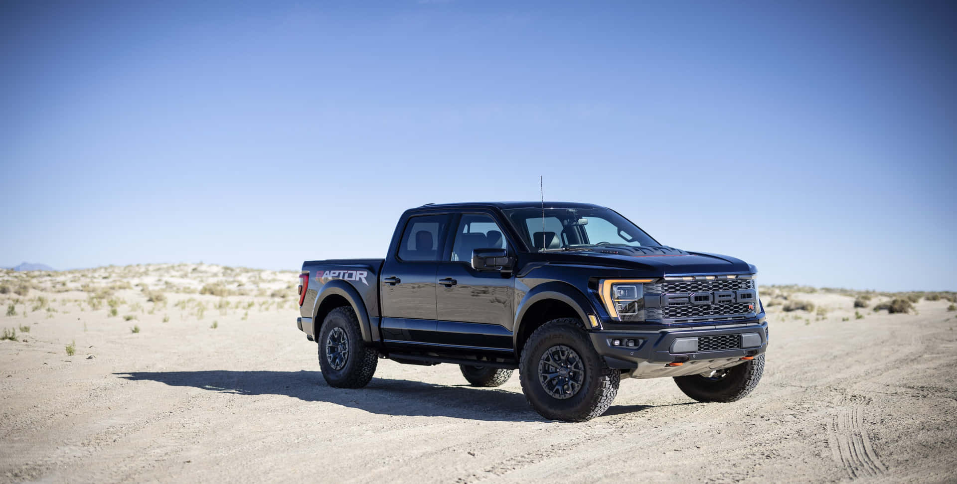 黑色福特F-150 Raptor卡車停在沙漠地形上，黃昏時分。