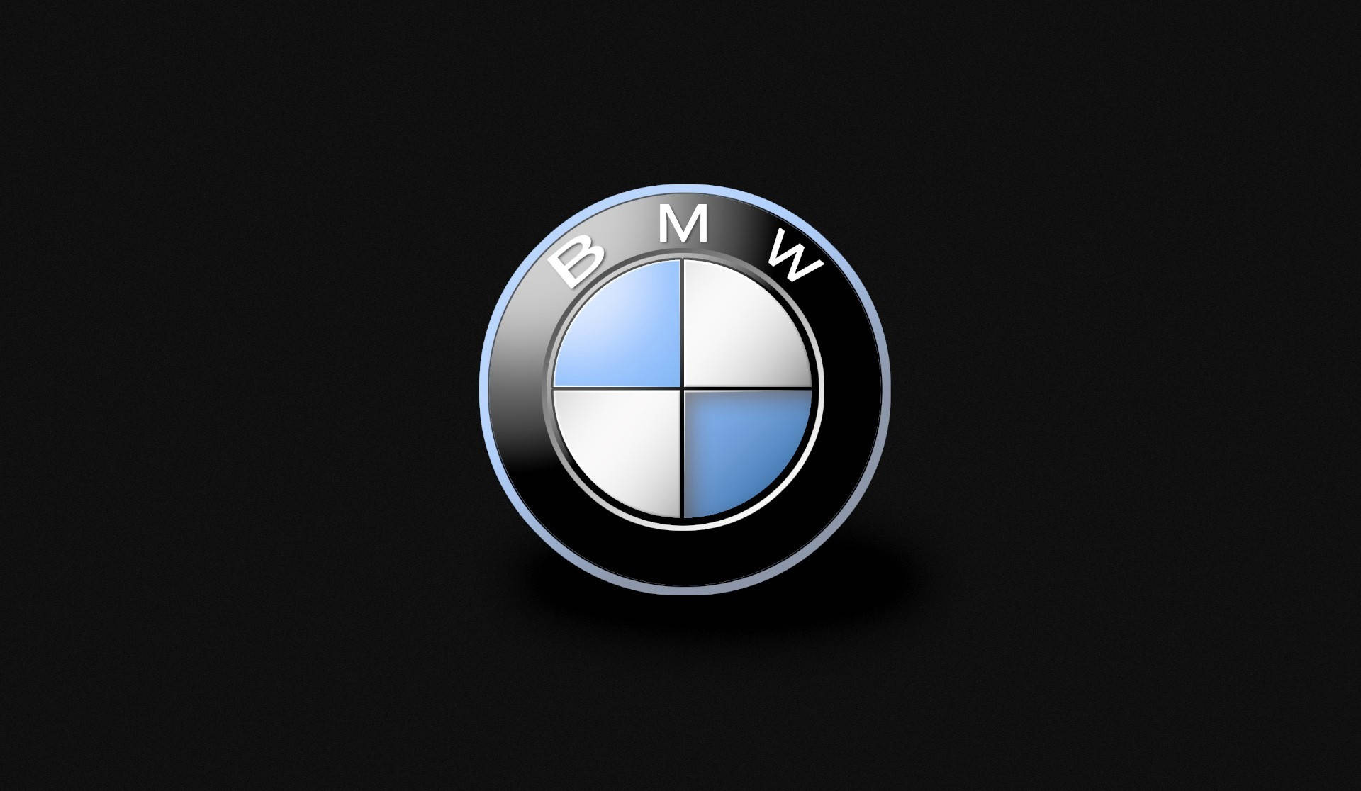 流線型黑色BMW穿行城市 壁紙 — 標誌性的BMW標誌在純黑背景上閃耀著金屬藍色和白色的四分之一圓。