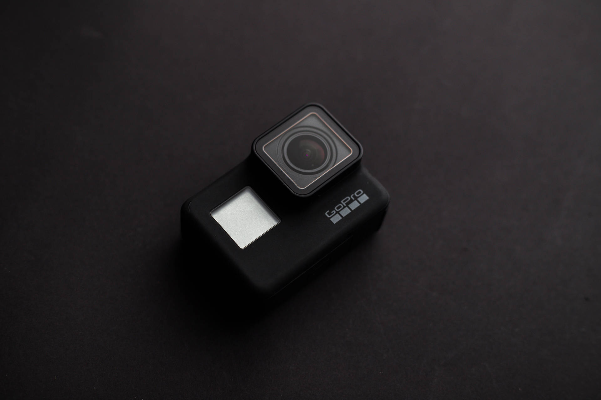流線型黑色GoPro 壁紙 — 一部時尚的黑色GoPro相機在柔和的工作室燈光下放置在磨砂深色表面上。