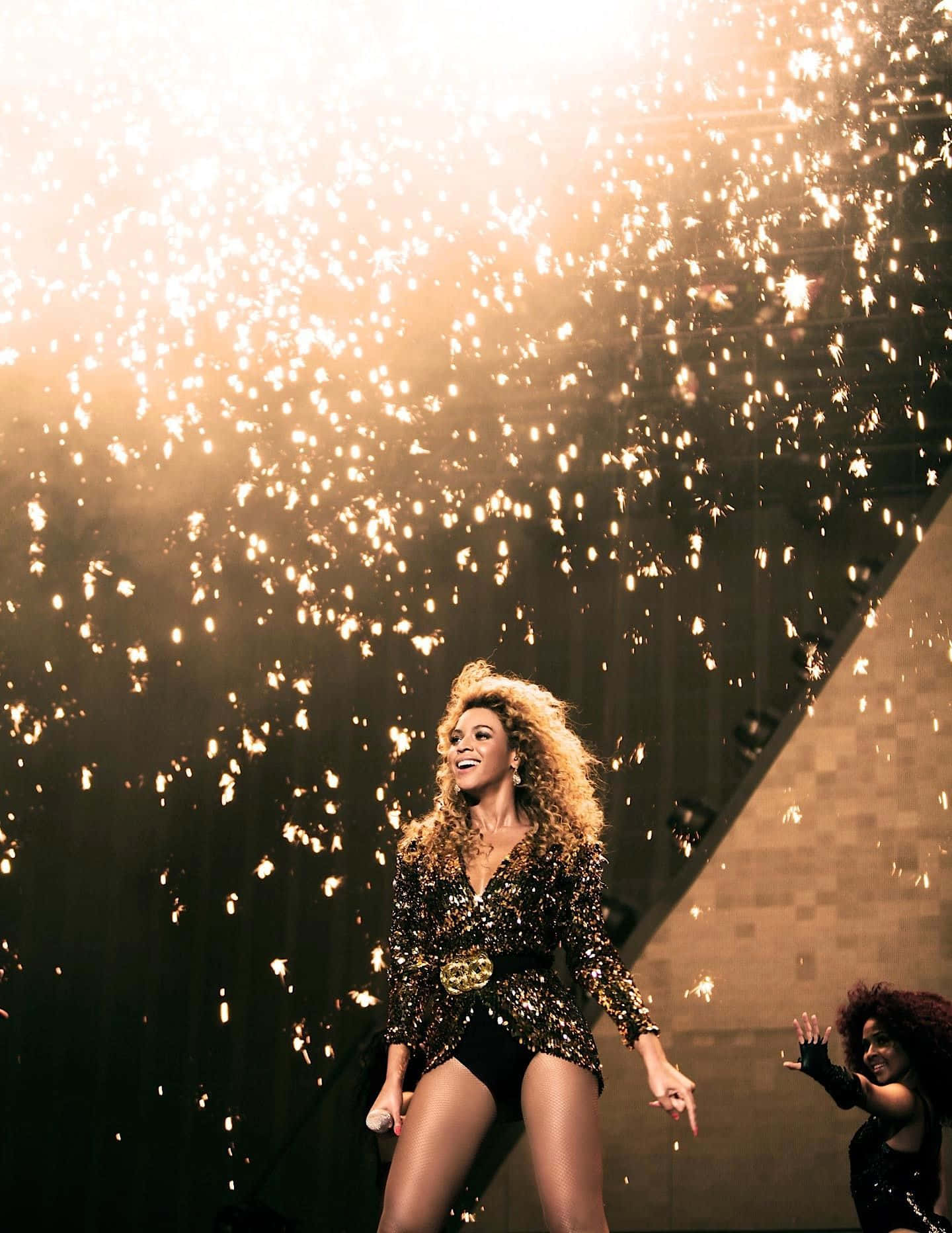 流行天后碧昂絲 壁紙 — Beyoncé 在舞台上散發喜悅，金色火花如瀑布般在她周圍灑落，構成一個耀眼的演唱會時刻。