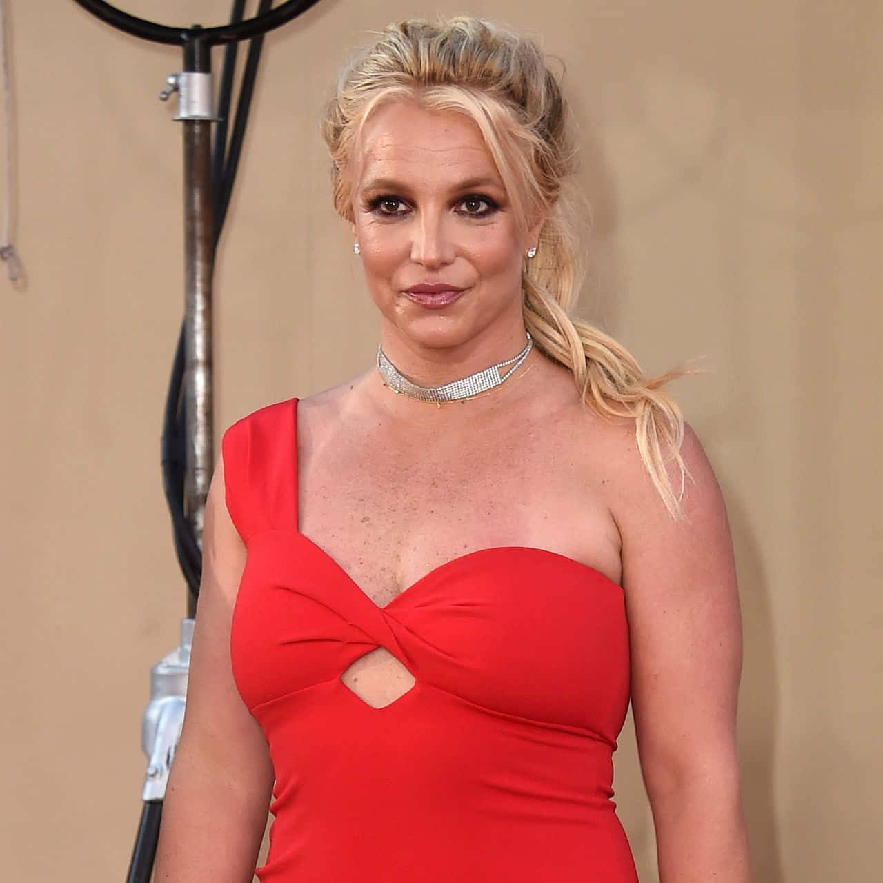 Britney Spears 在正式活動中穿著紅色連衣裙和鑽石頸鏈。