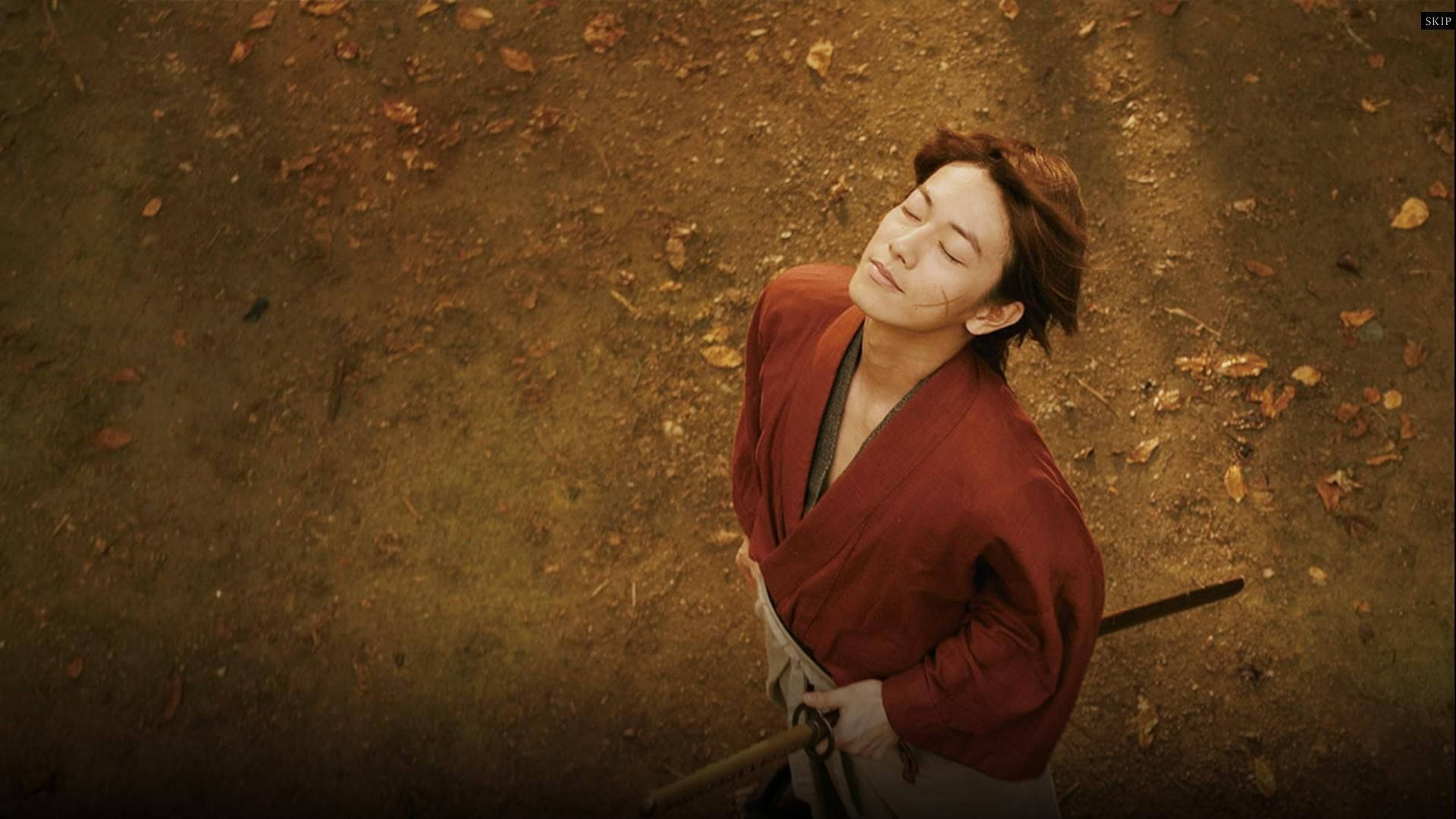 浪客劍心感受微風 壁紙 — 一位身穿紅袍的寧靜武士在散落著秋葉的森林地面上閉目休息。