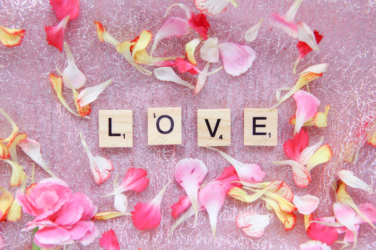 拼出 love 的拼字磚，在閃亮的粉紅色背景上被粉紅色和黃色花瓣包圍。
