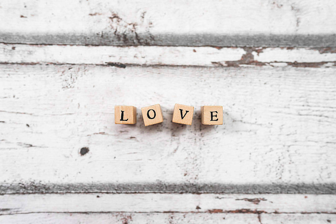 在磨損的白色木質背景上拼出 LOVE 的木塊。