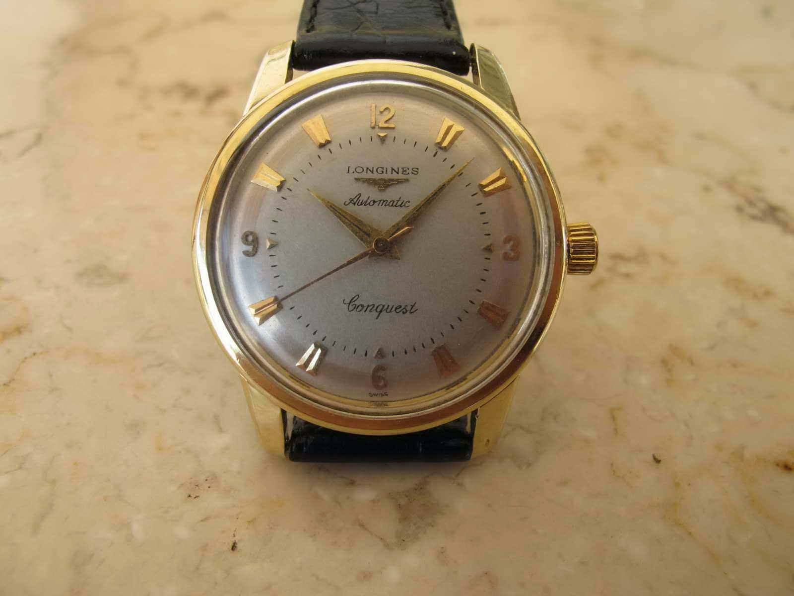 復古金色Longines腕錶，黑色皮革錶帶，大理石上。