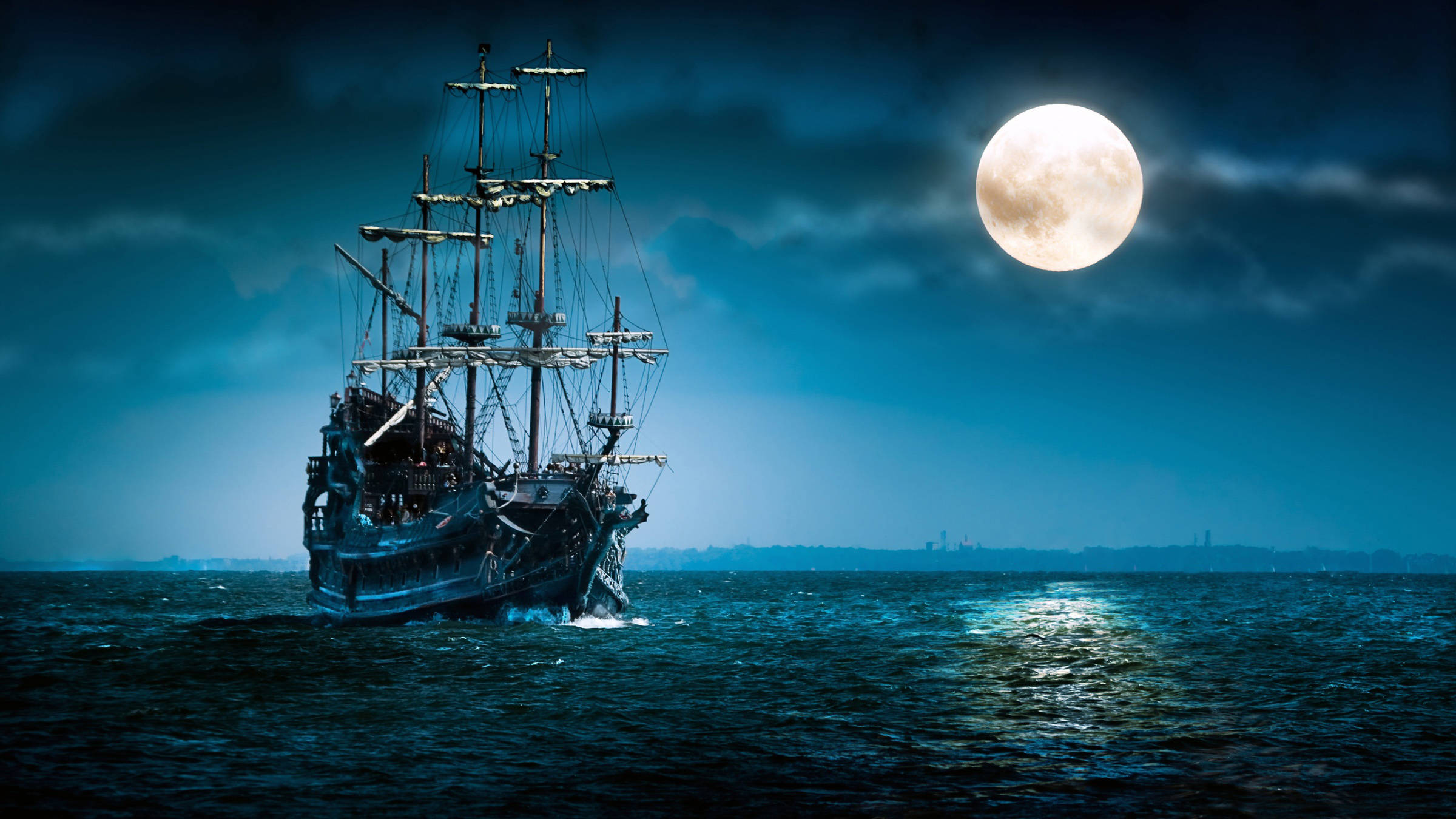 海上午夜 壁紙 — 一艘雄偉的海盜船在夜間深藍色的海洋上，在發光的滿月下航行。