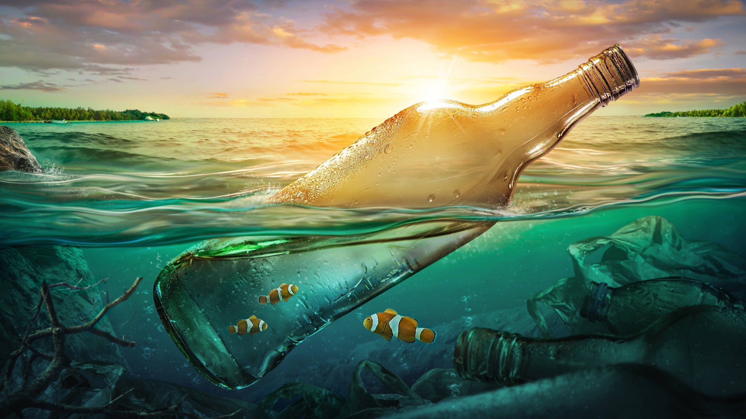 海中的瓶子 壁紙 — 一個玻璃瓶在日落時漂浮，小丑魚在岩石附近的水中在瓶內游動。
