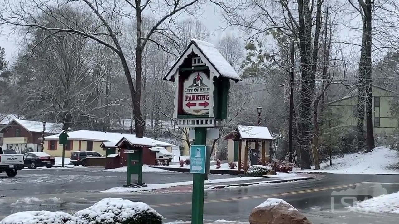 白雪覆蓋的街道標誌，在寧靜的冬季城鎮中，有光禿的樹木和停泊的汽車。