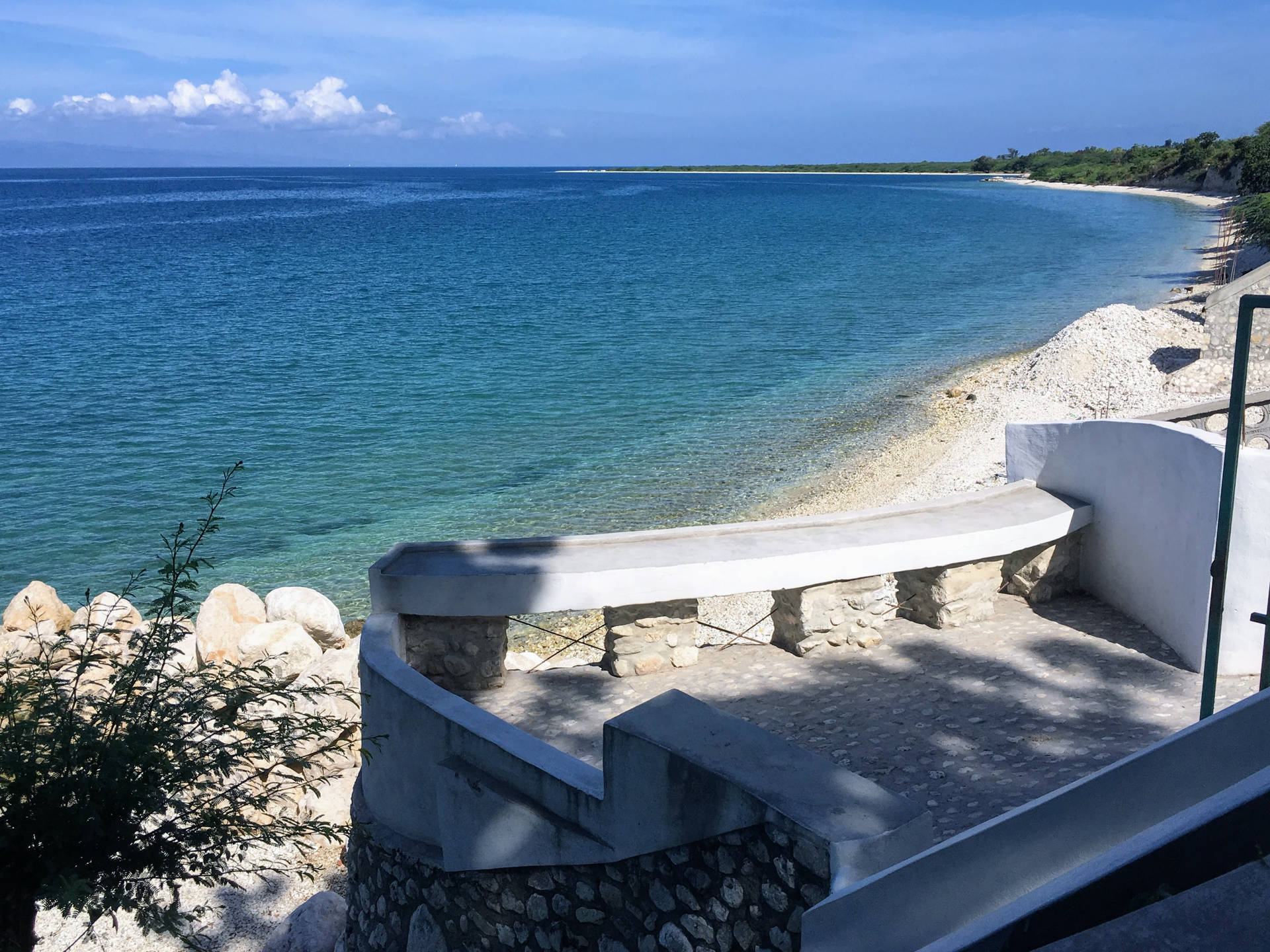 彎曲的混凝土長椅，在陽光明媚的日子裡俯瞰碧綠的海水和岩石海灘。