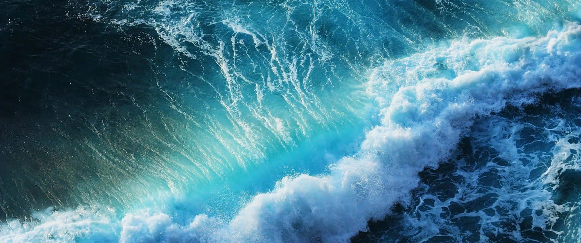 一道巨大的海浪正在破碎，帶有藍綠色泡沫和深藍色海水。