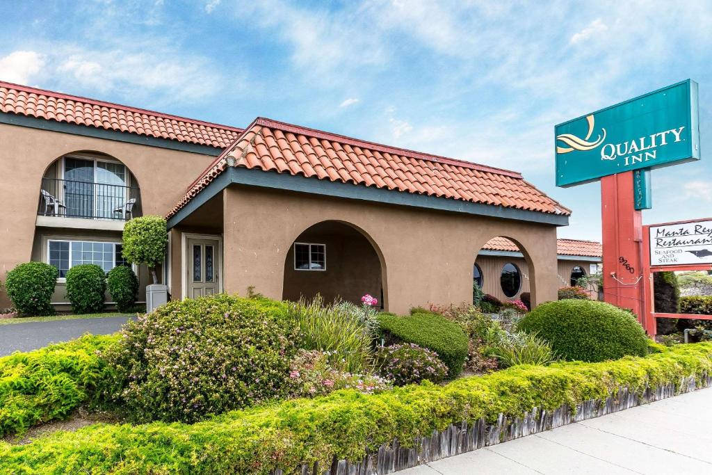 Quality Inn 酒店，紅色瓦片屋頂，綠色園景，藍天白雲