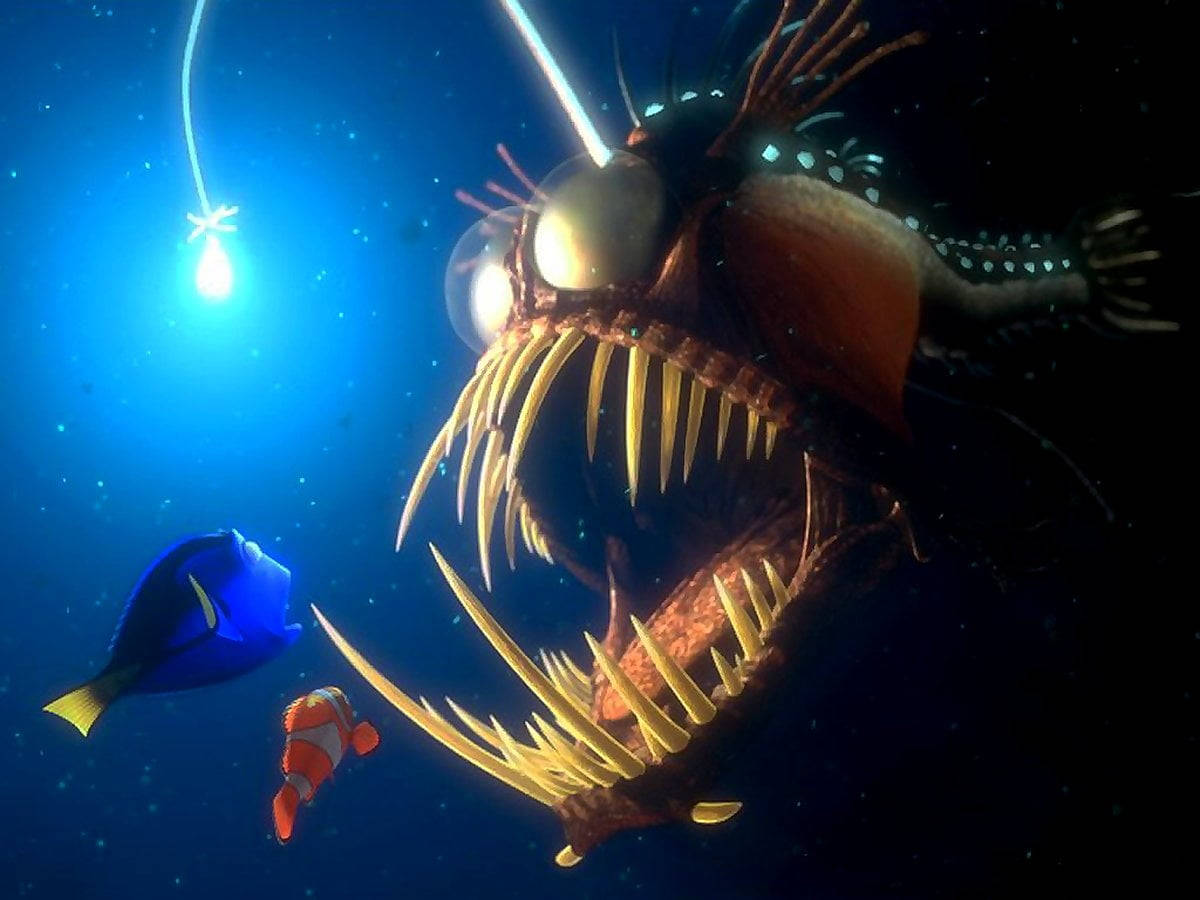 海底總動員：發光的燈籠魚 壁紙 — 一條巨型琵琶魚，帶有發光的誘餌和鋒利的牙齒，在深海黑暗中籠罩著小丑魚和藍色刺尾魚。