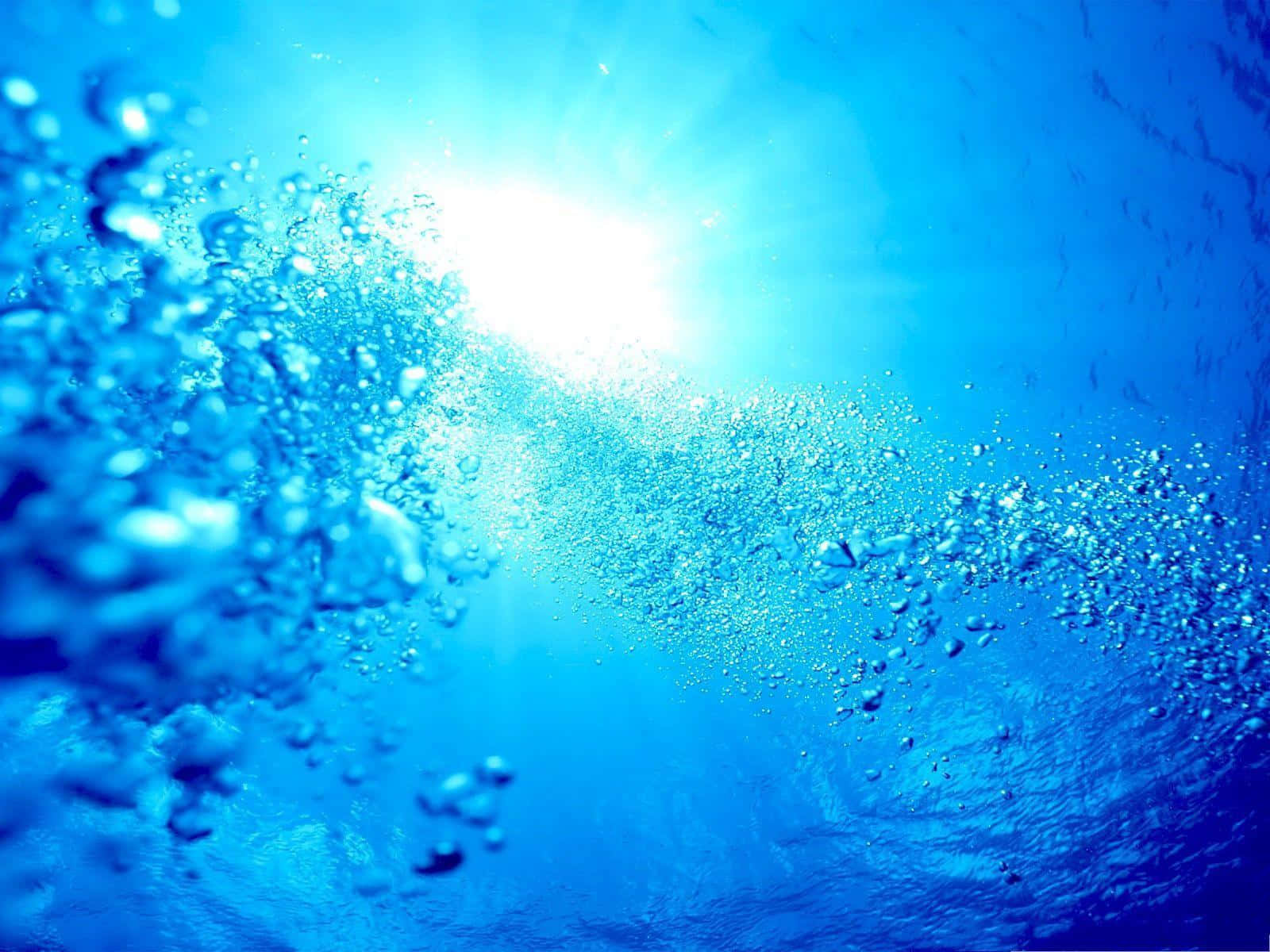 海底藍水氣泡 壁紙 — 氣泡在清澈的藍色水中上升，陽光從上方照射下來，形成耀眼的水下光芒。