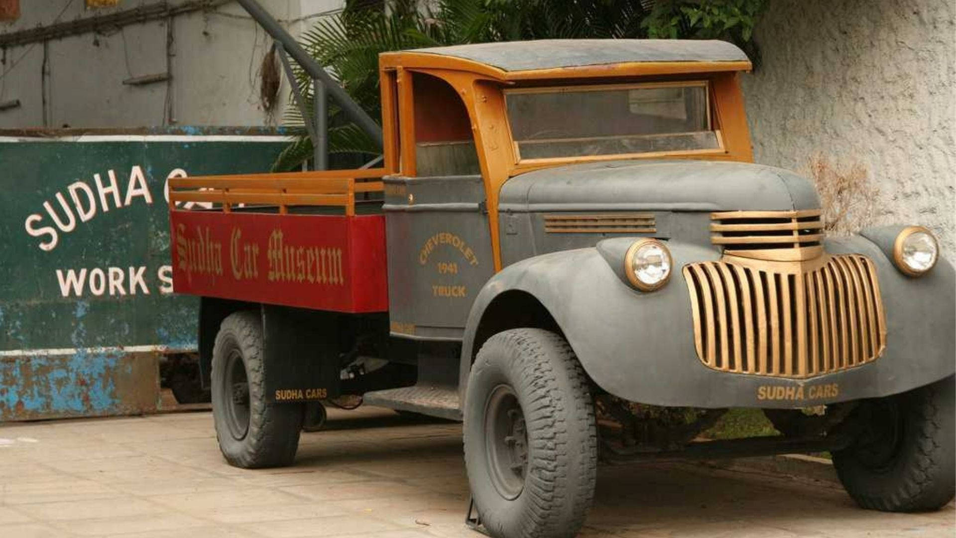海得拉巴蘇達汽車博物館精彩收藏 壁紙 — 經典1949年雪佛蘭卡車，帶橙色點綴和紅色貨斗，停泊在Sudha Car Museum外。
