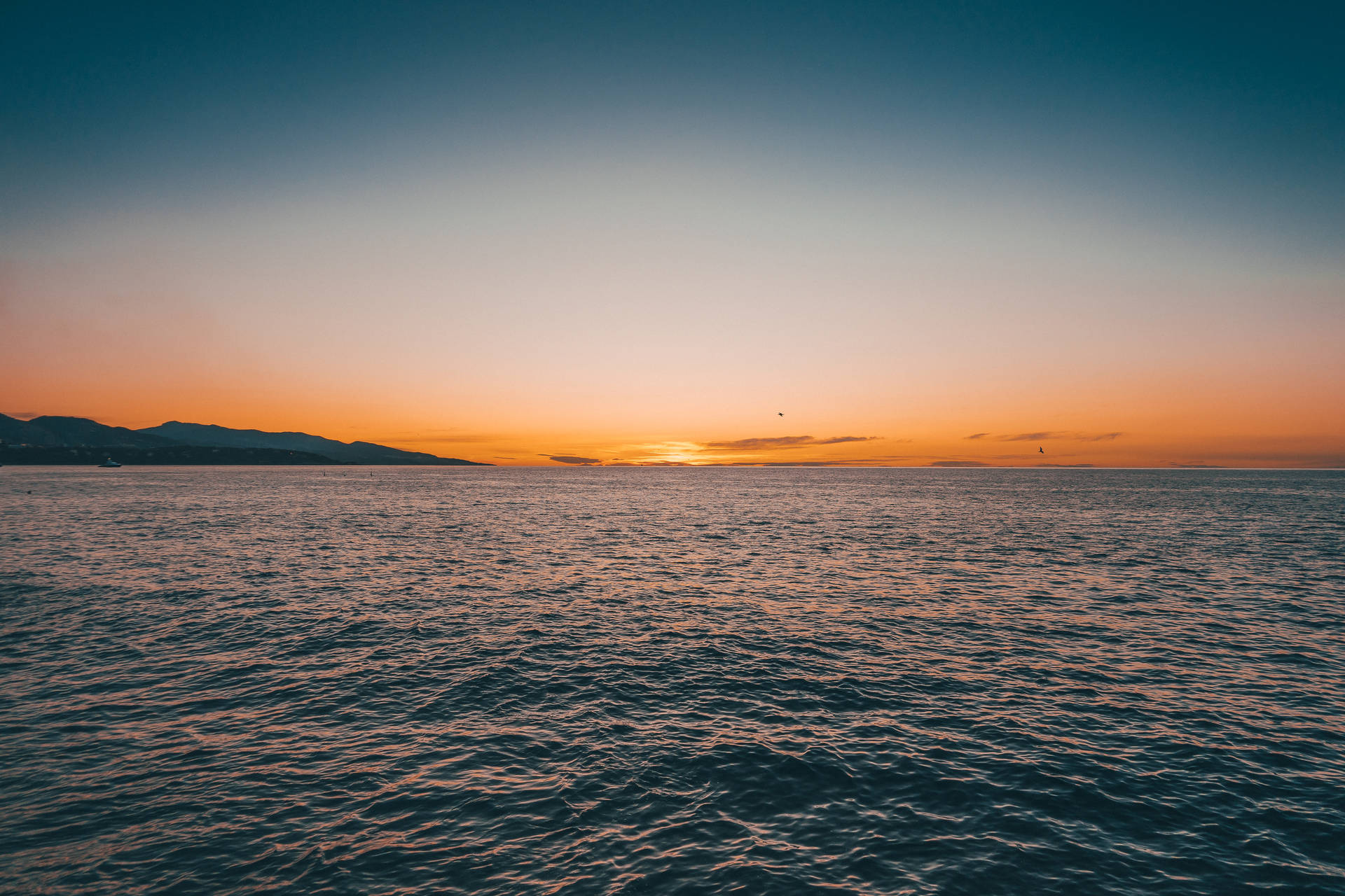 夕陽映照海面，遠山在望