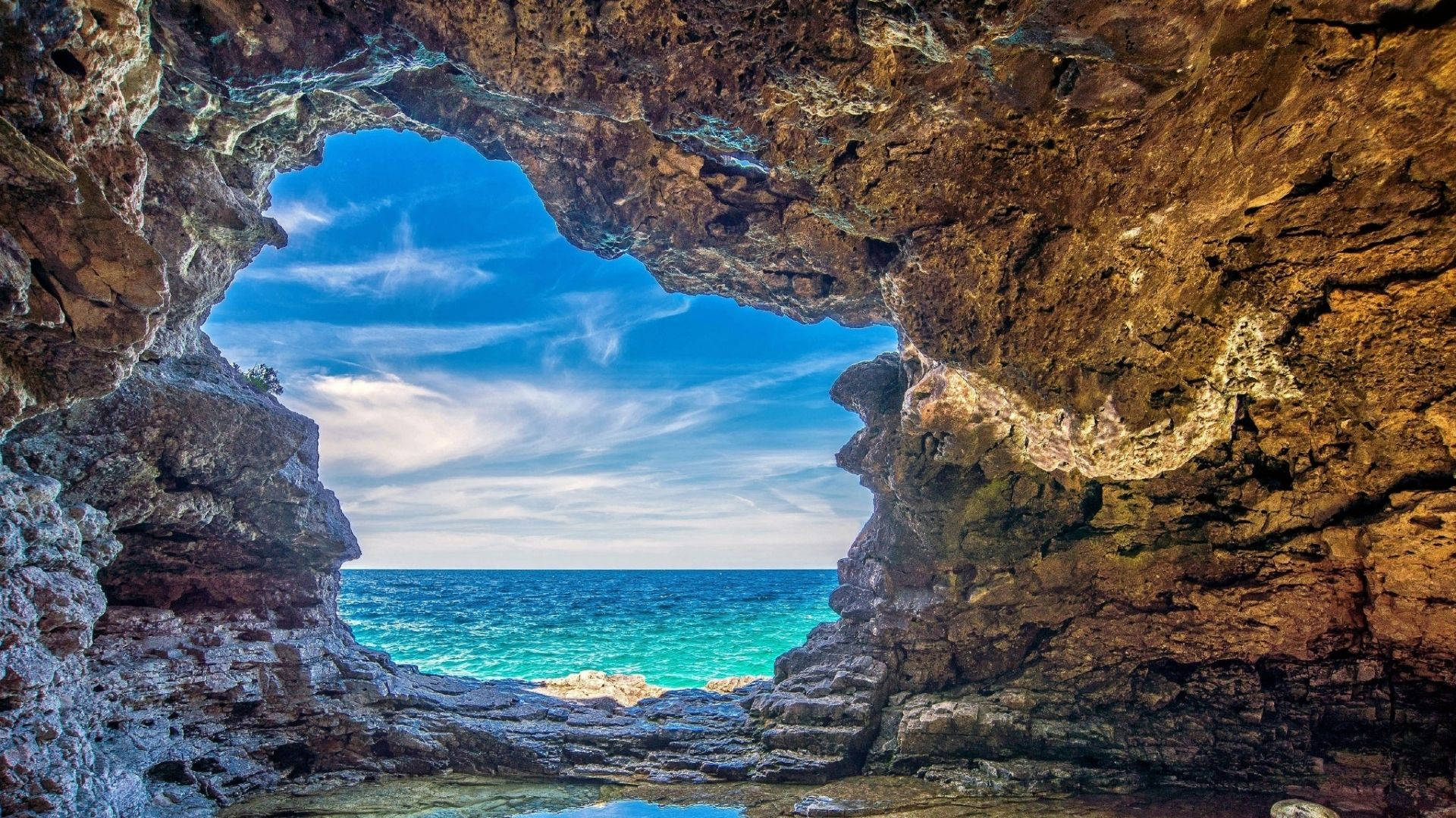 透過岩石洞穴開口望向碧綠海洋和藍天。