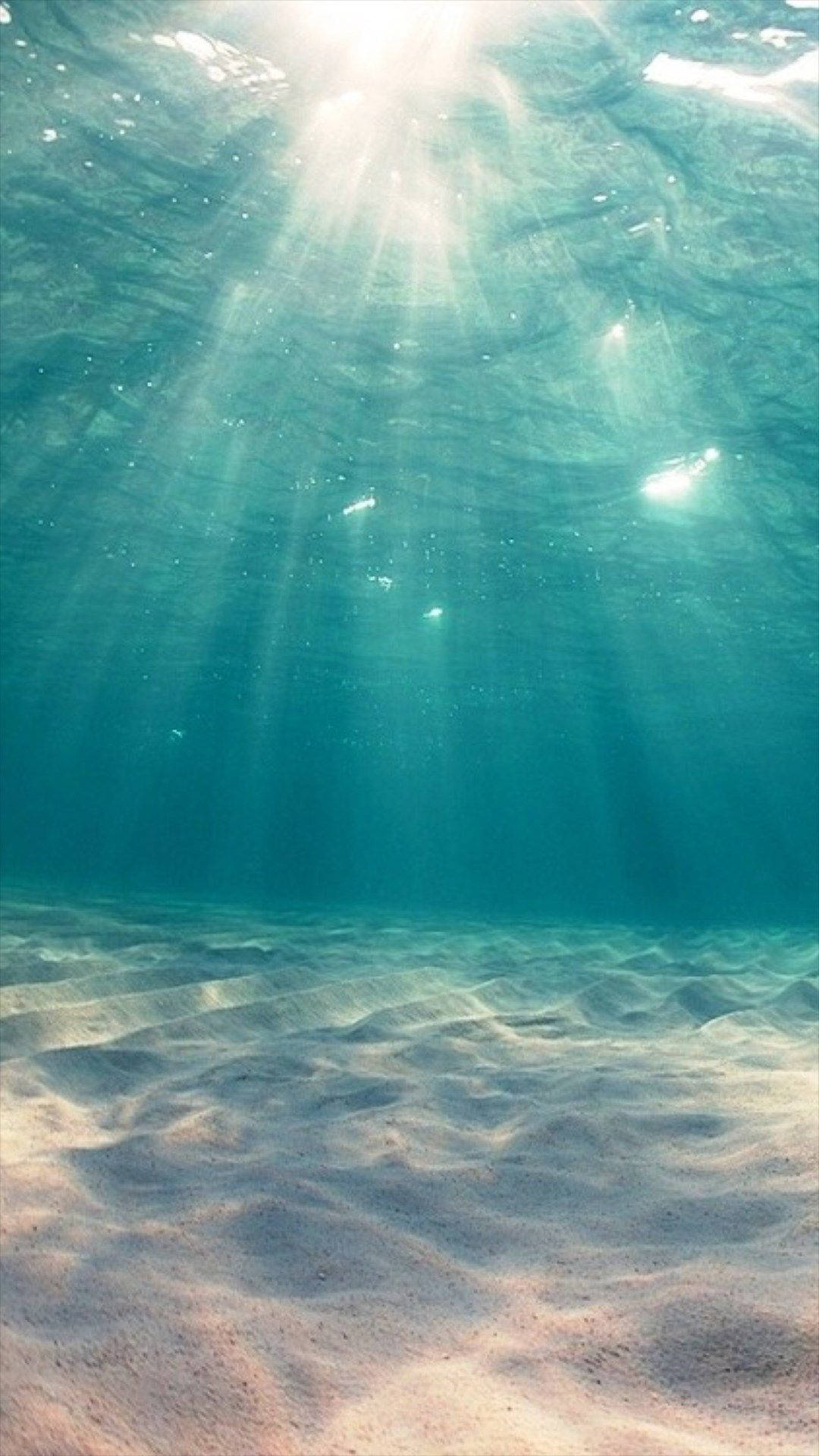 陽光穿過清澈的海水照射到沙質海床上。