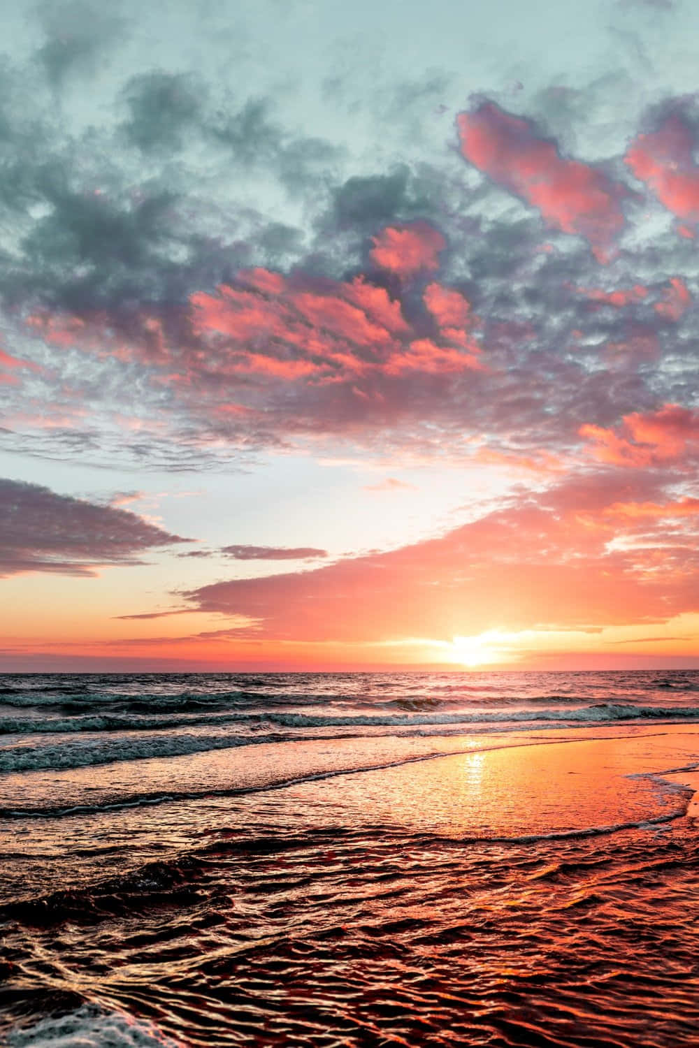 Sunset Photography 桌布 壁紙 — 海洋上令人驚嘆的日落，充滿活力的粉紅色、橙色和藍綠色雲彩反射在漣漪的水面和濕沙上。