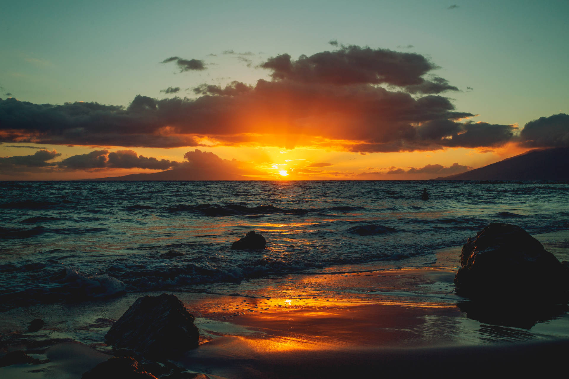 夕陽映照海洋，海浪拍打岩石海灘