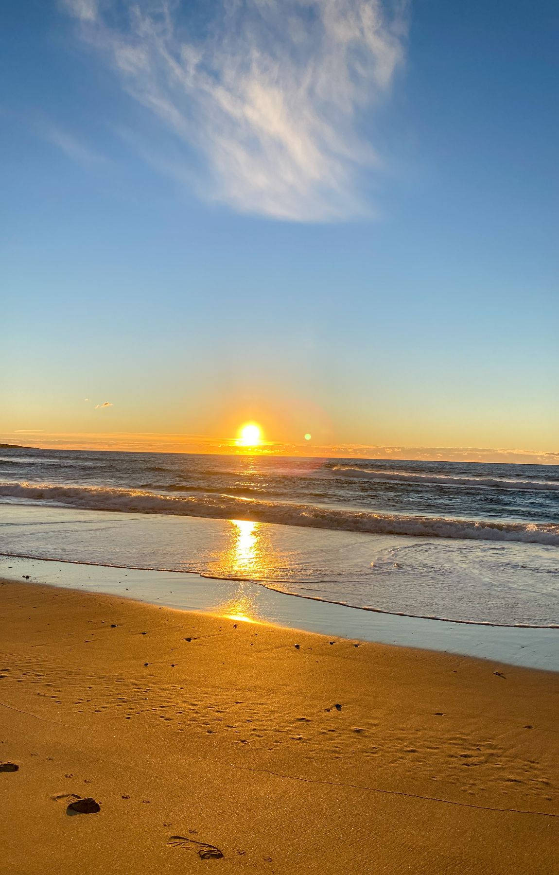 夕陽下的海洋，沙灘上有海浪